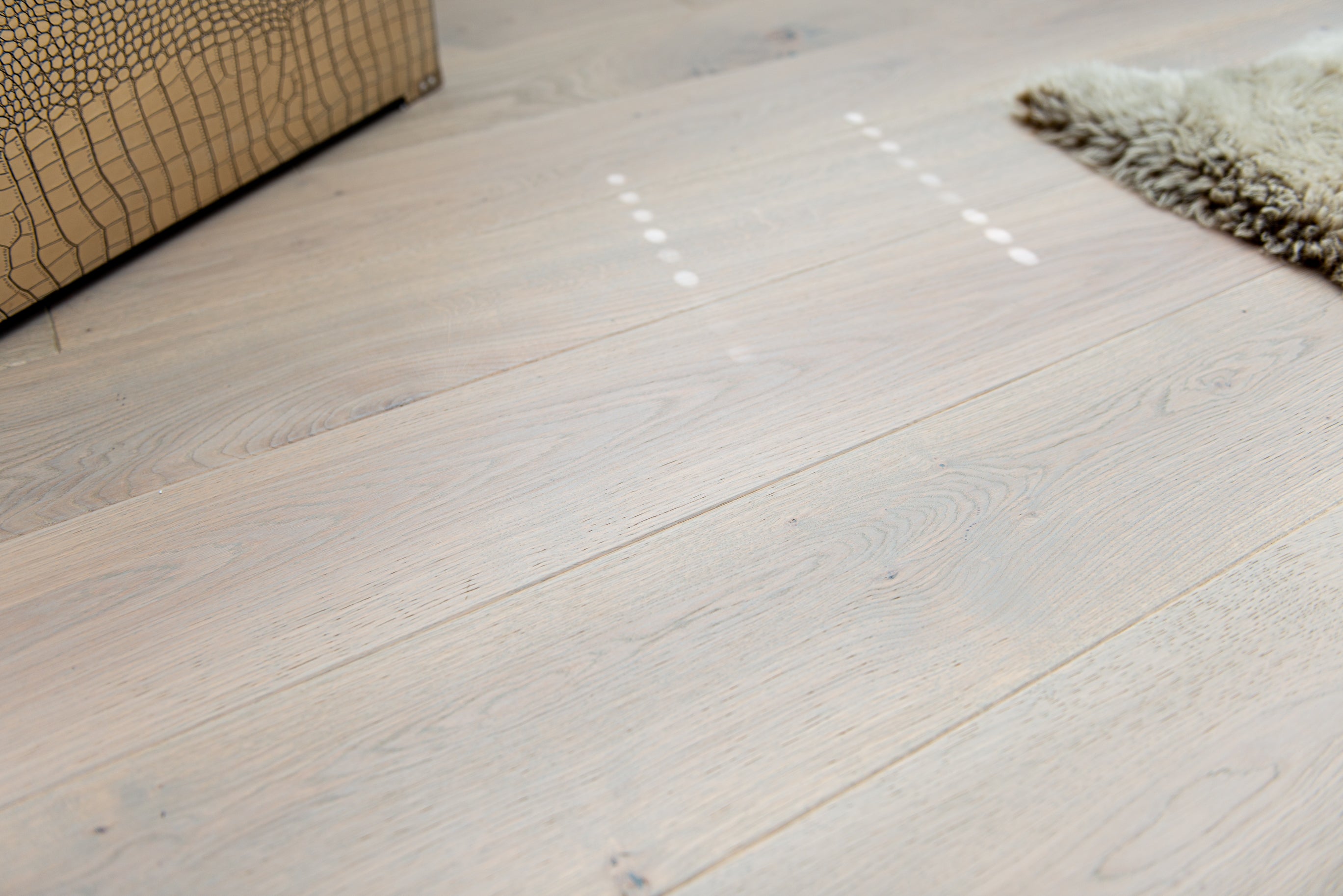 Close-up of light-coloured driftwood wooden flooring with a textured wall in the background