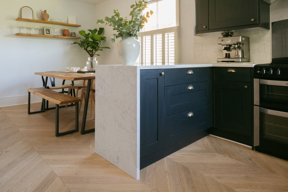 blue kitchen with white marble island and seashell chevron wood floors