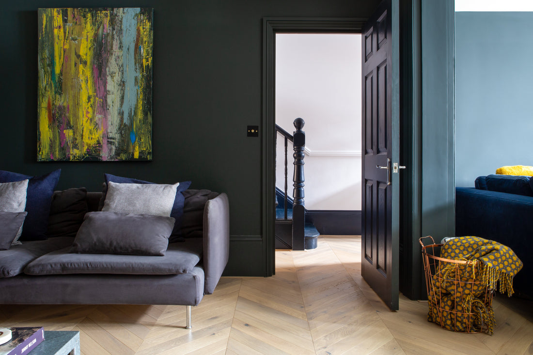 living room with dark green walls and light oak chevron wood floors