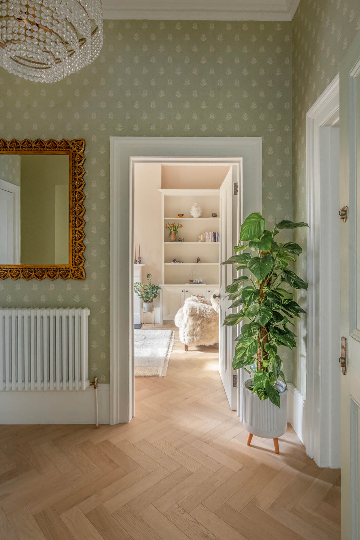 Hallway with patterned wallpaper and light oak herringbone wood floors