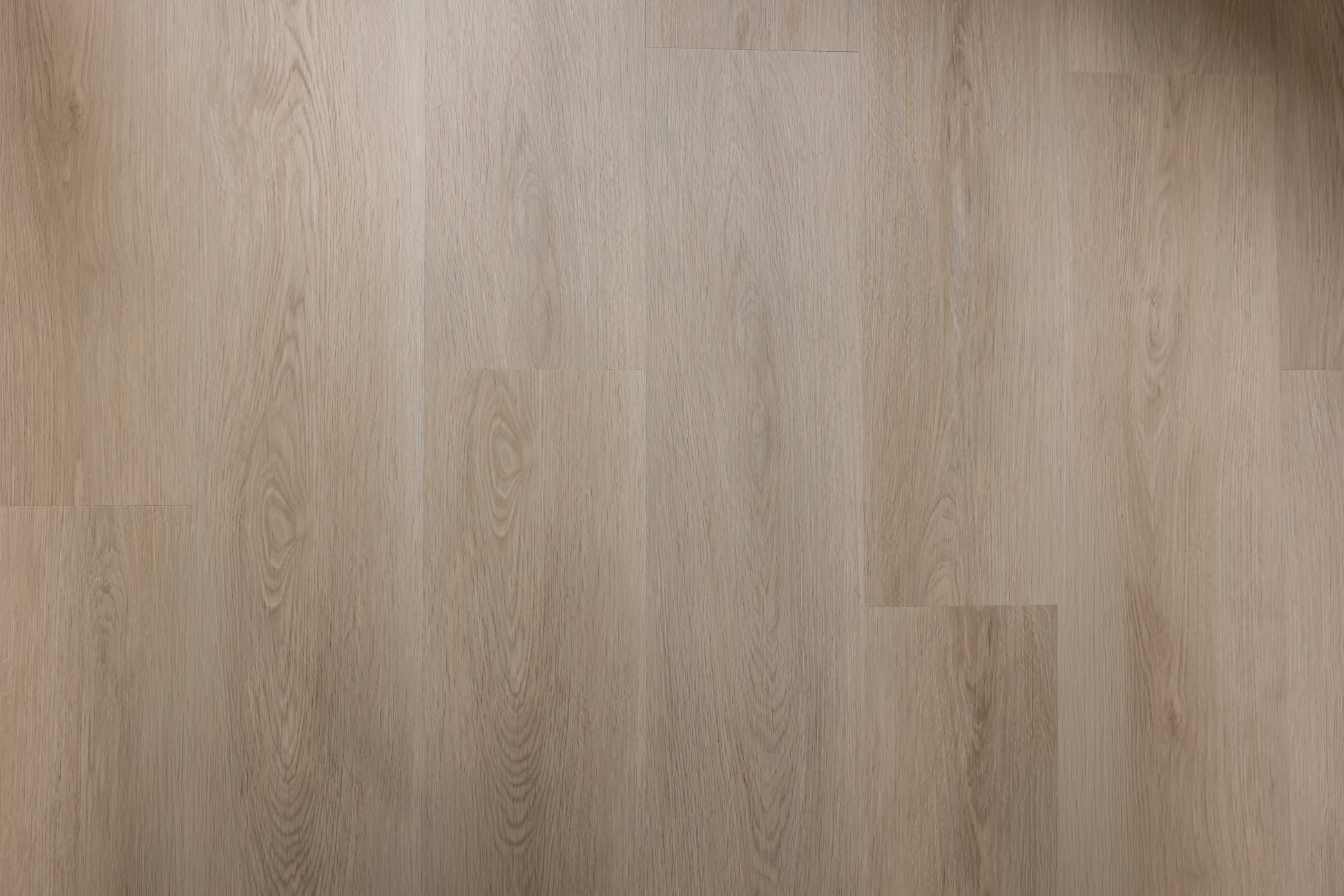 Close-up of a wood-effect SPC vinyl floor with a light brown color and visible grain pattern.