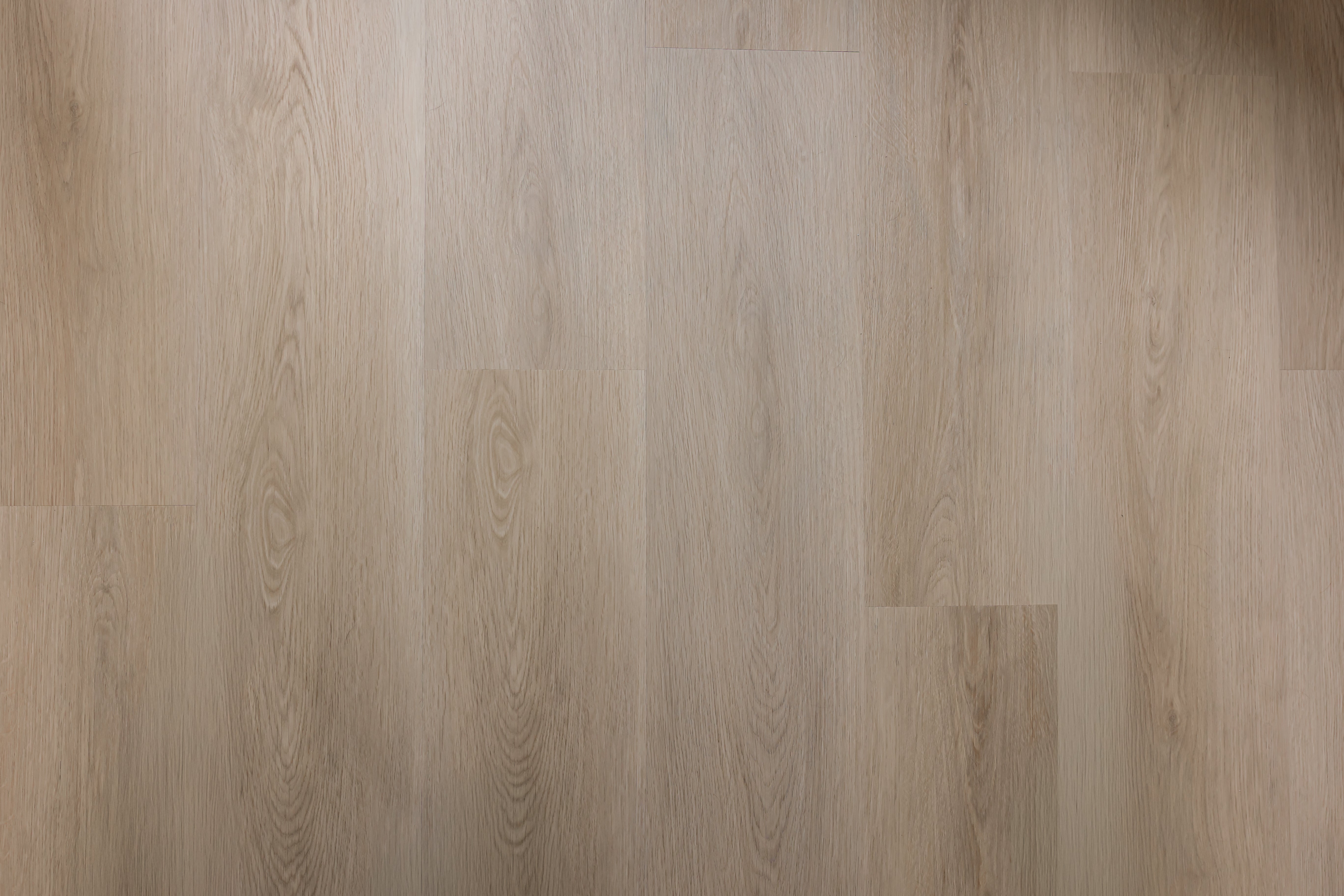 Close-up of a wood-effect SPC vinyl floor with a light brown color and visible grain pattern.