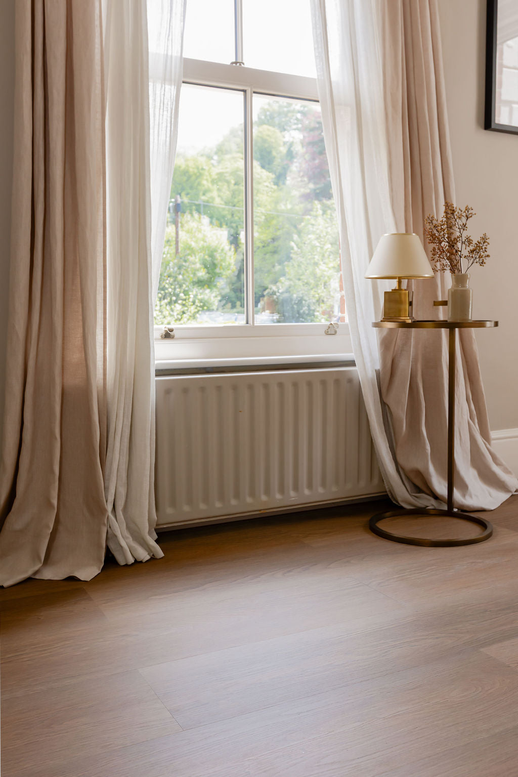 A warm and golden oak effect SPC vinyl click floor installed by a bright living room window