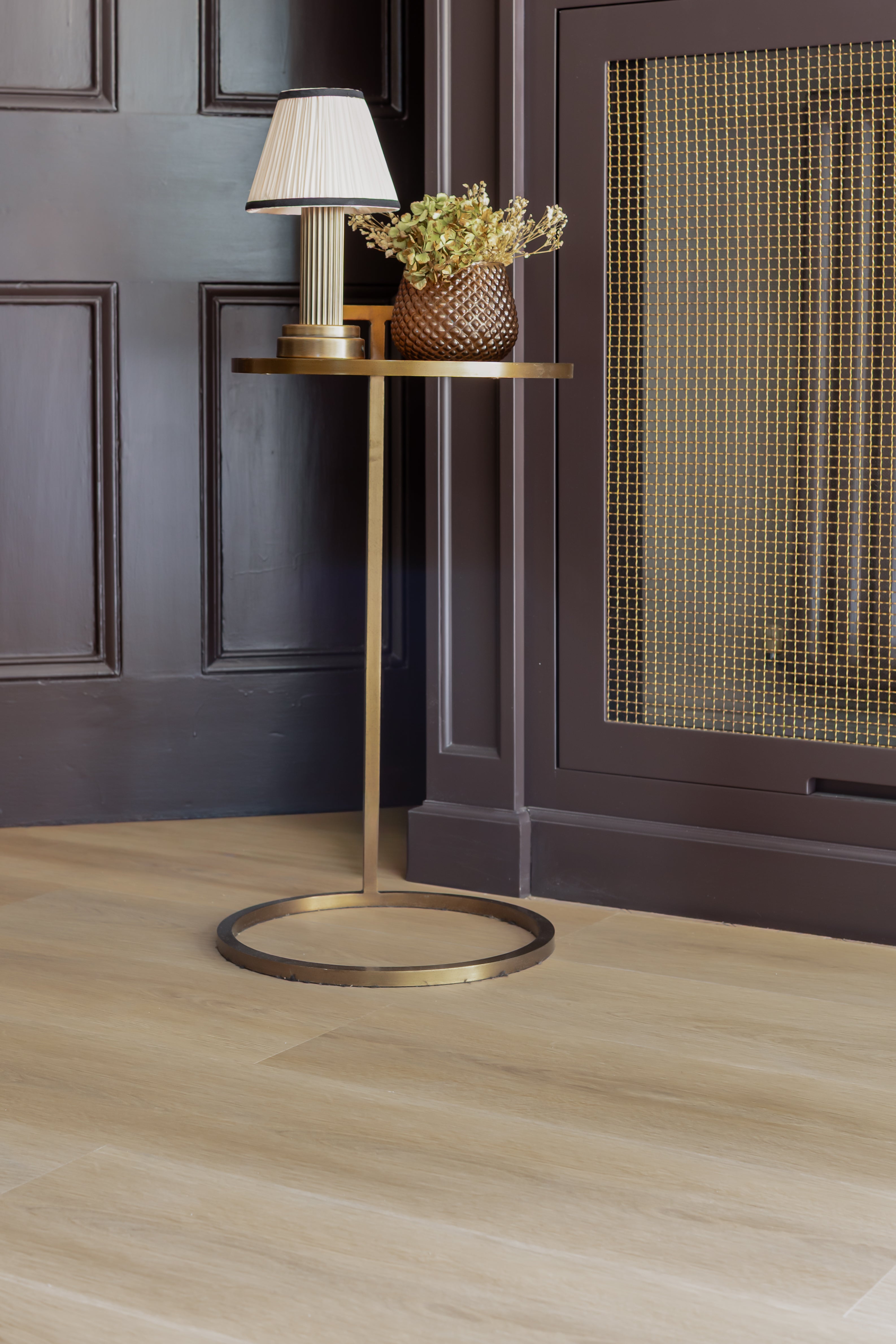 A gold side table with lamp sitting on top of the light golden oak wood-effect SPC click vinyl floor