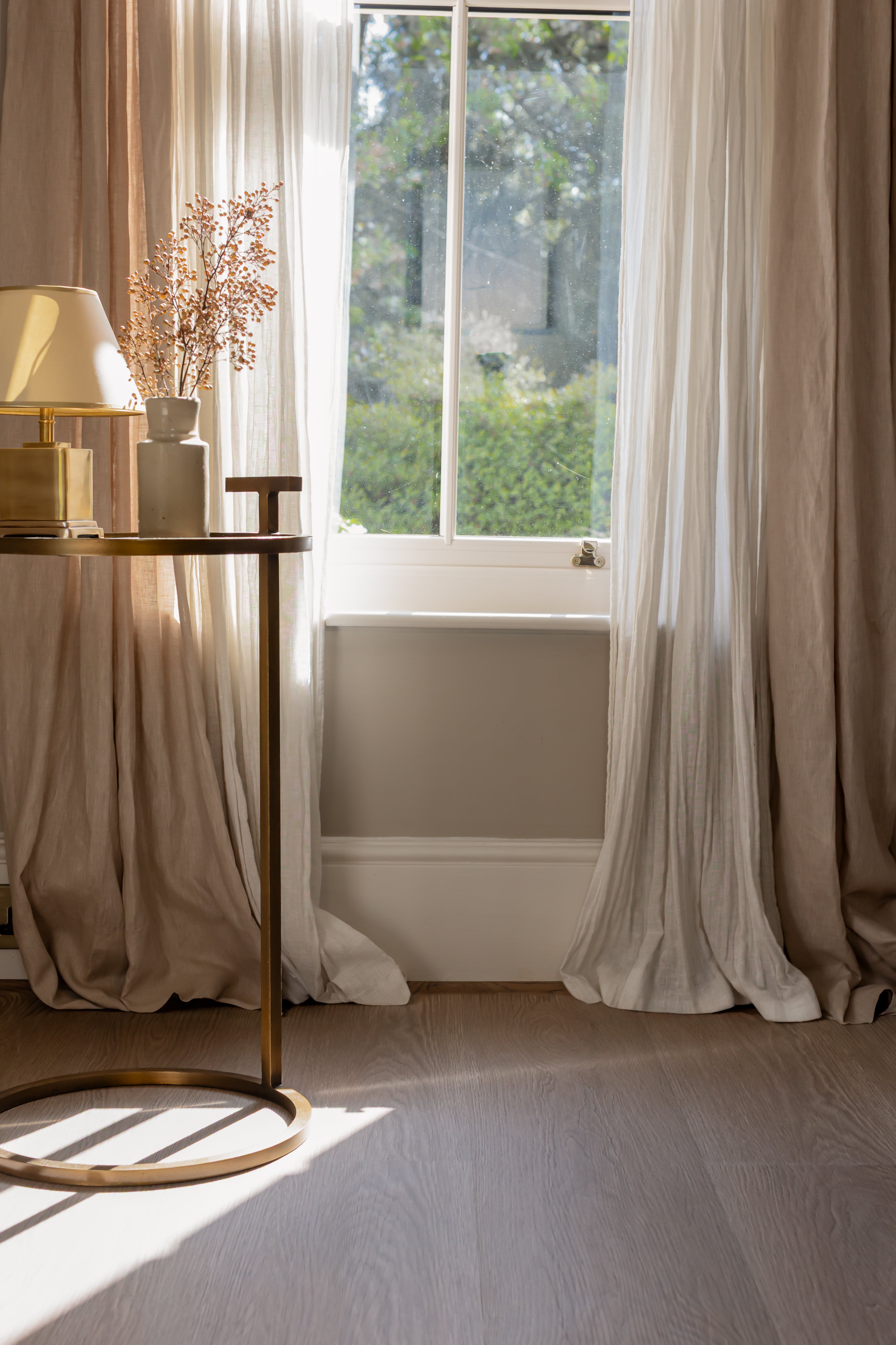 Brown and grey toned click SPC floor with a lamp and plant on a wooden side table.