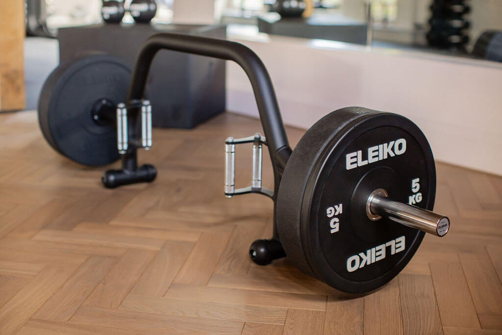Eleiko weight plate on a wooden floor with gym equipment in the background