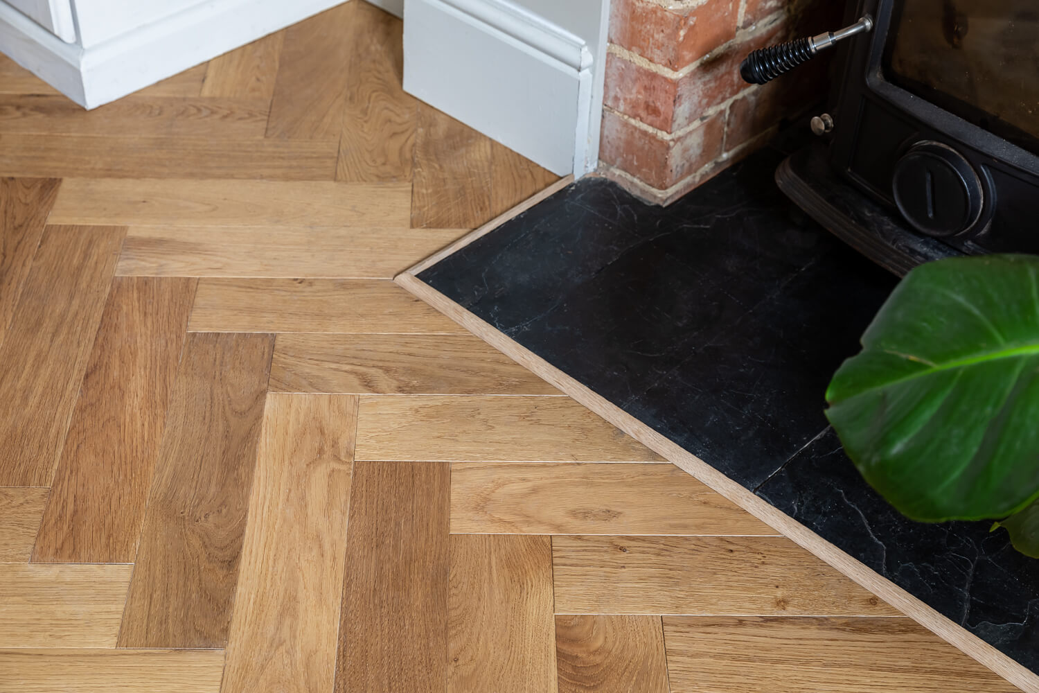 Wooden floor with a herringbone pattern near a fireplace.