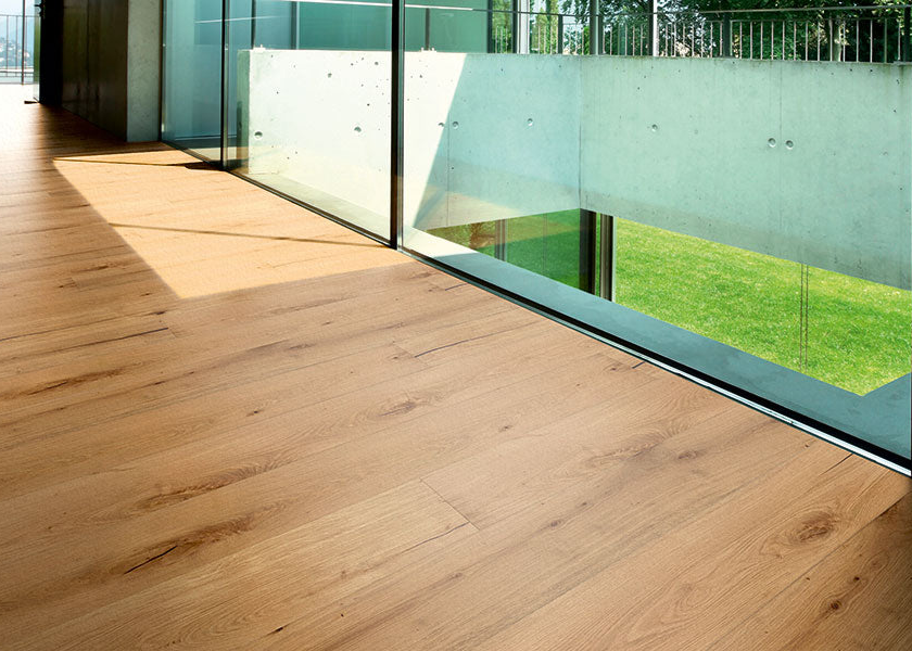 Wooden deck with glass panels showing a view of grass and trees