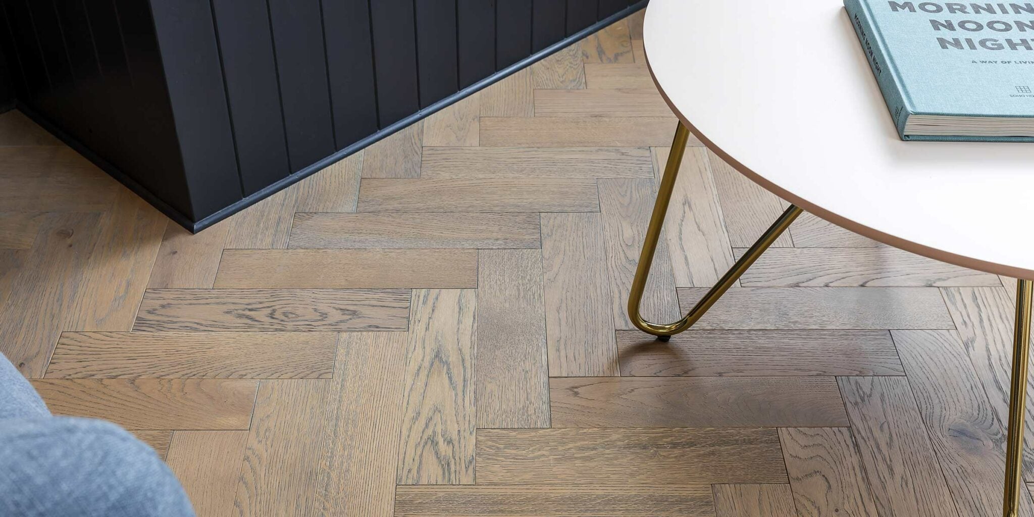 Wooden herringbone flooring with a coffee table and book in a room setting