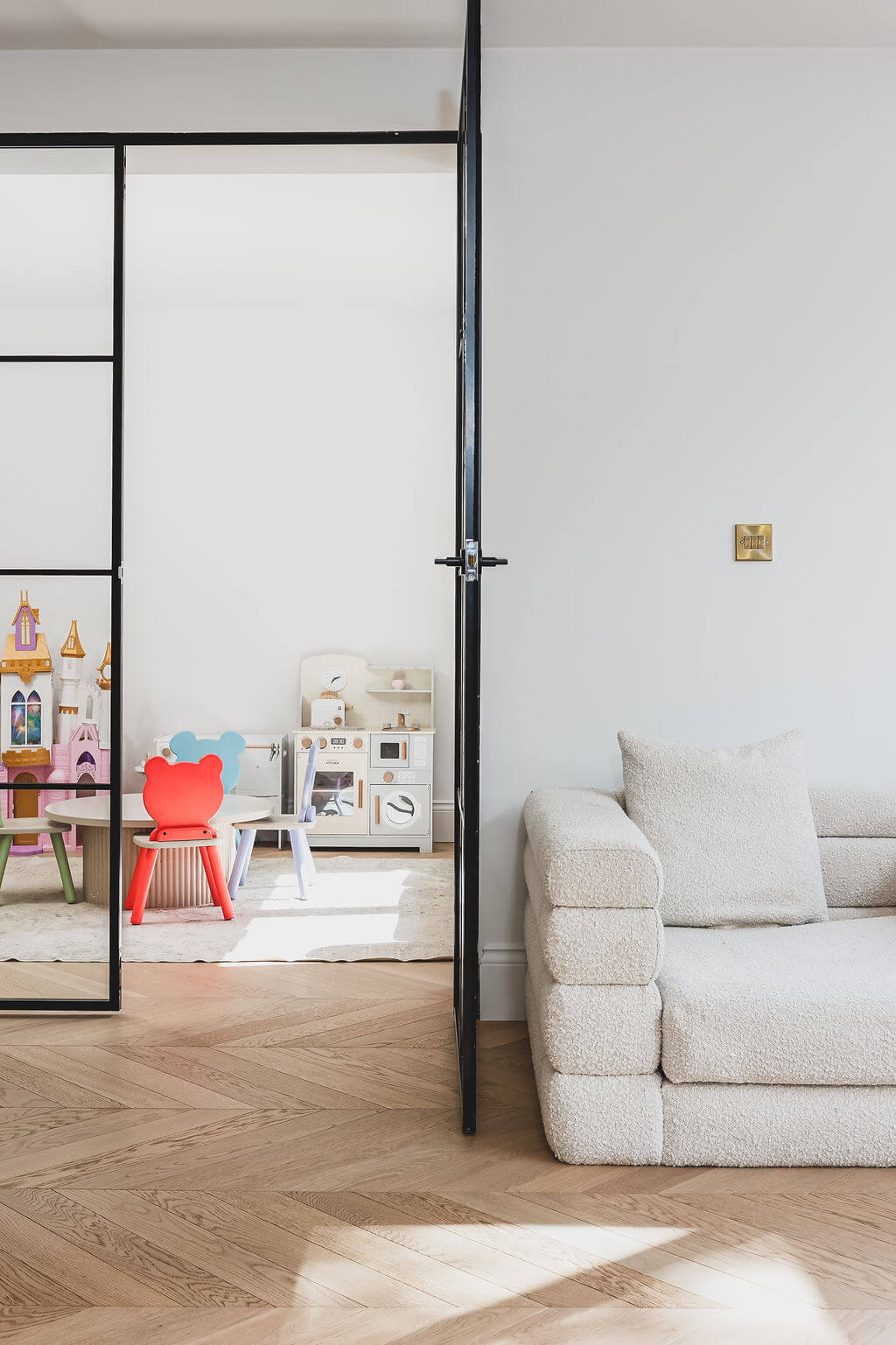 Crittall doors connecting a playroom and living room with Tundra chevron wood flooring