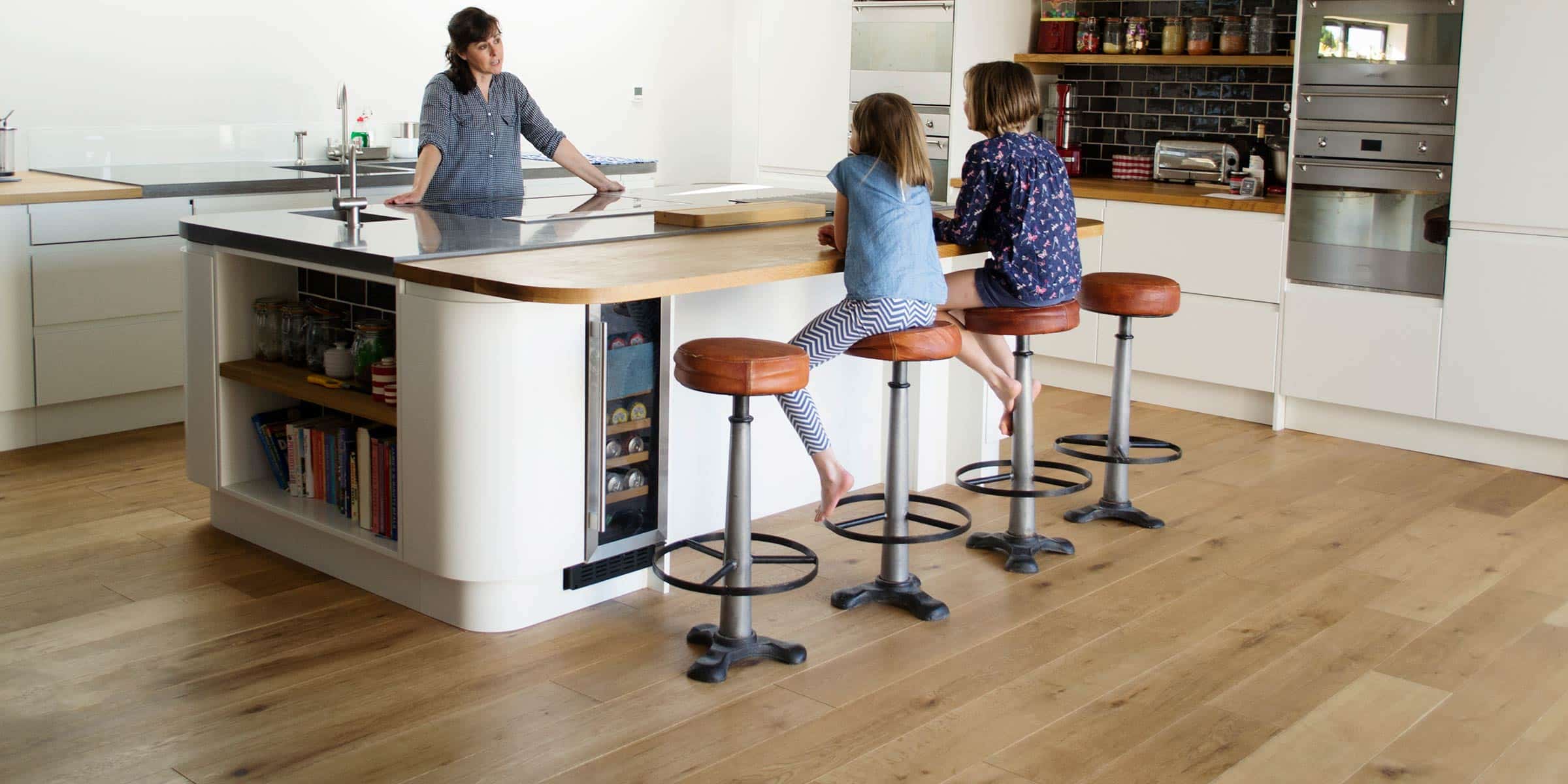 A mother and two children in a large kitchen with oak wood floors