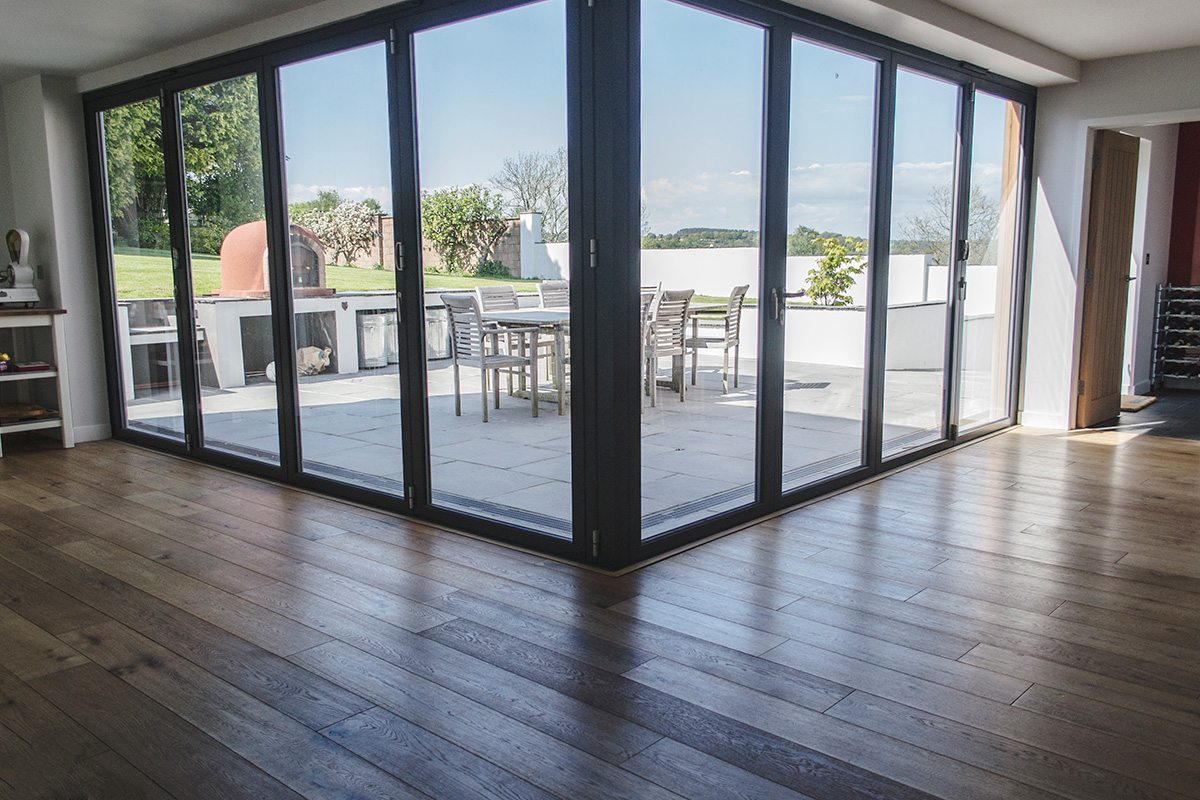 brushed oil oak wood floors with large floor to ceiling windows leading to an outdoor patio