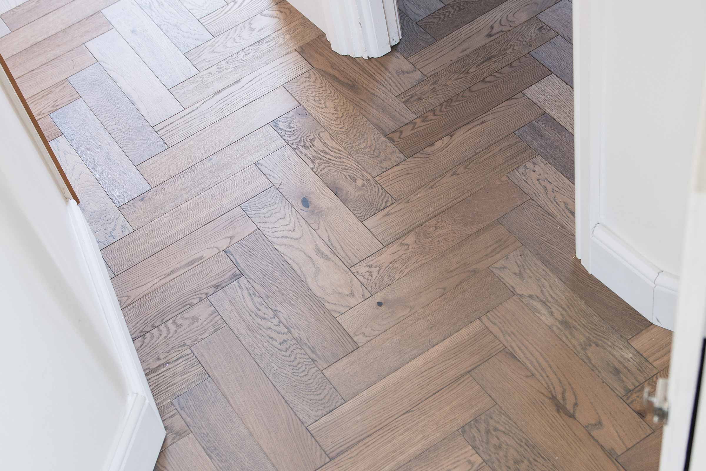 close up of herringbone parquet flooring in a hallway with white walls