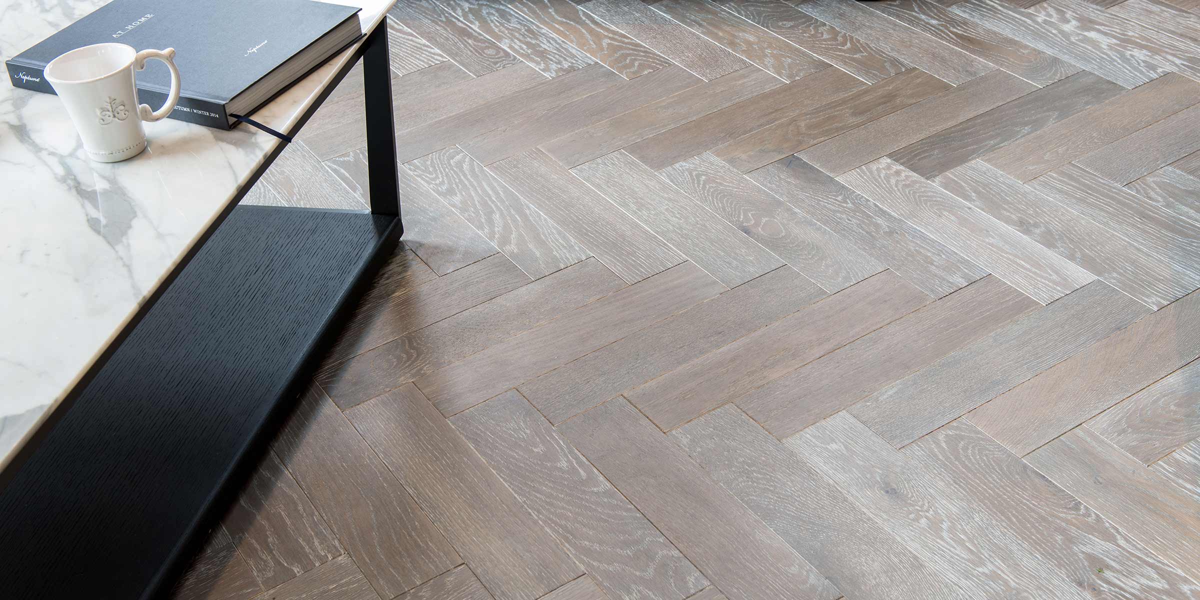 herringbone wood floors with a marble coffee table on the left