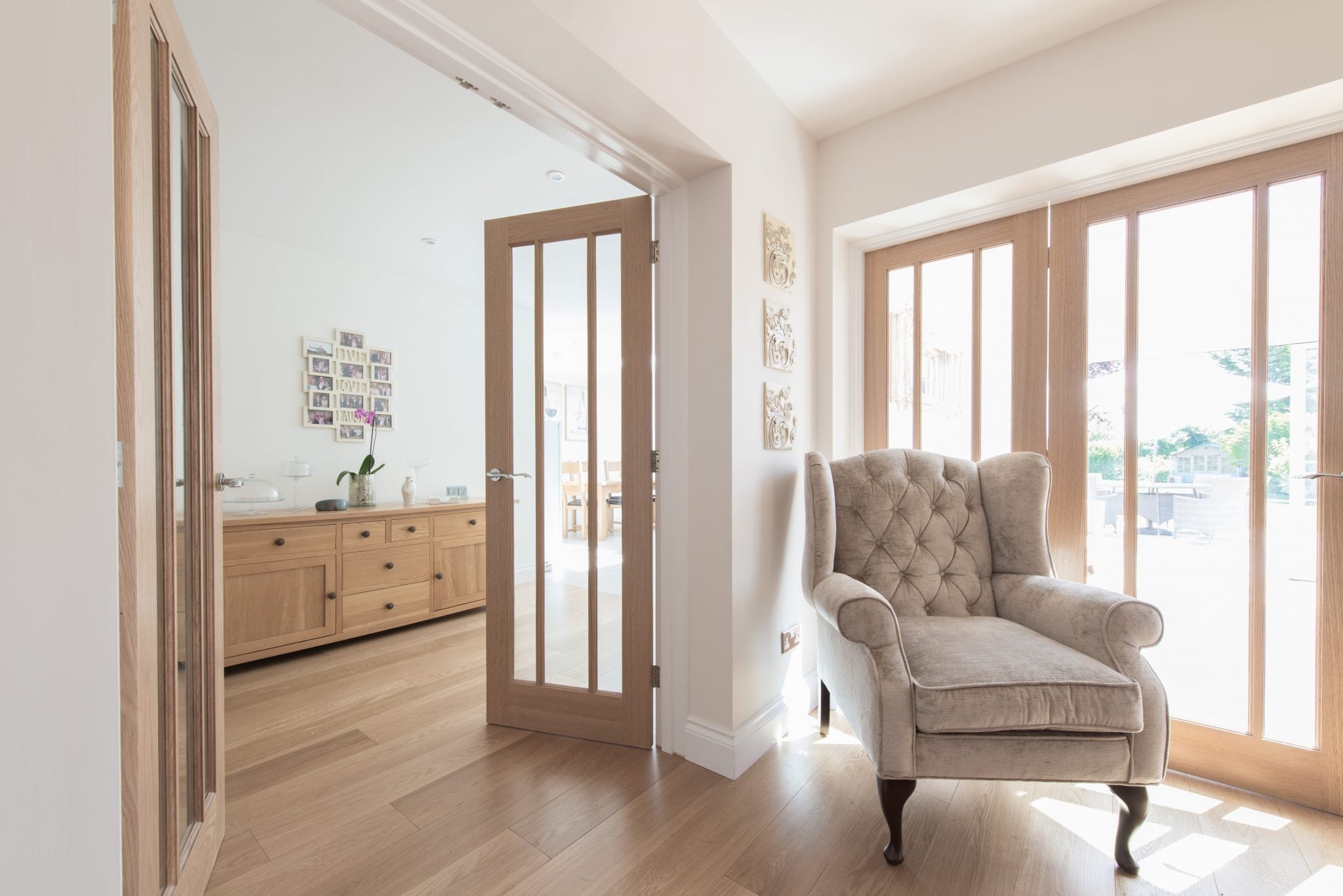 wide alpine plank oak floors in a bright airy living room with a beige armchair