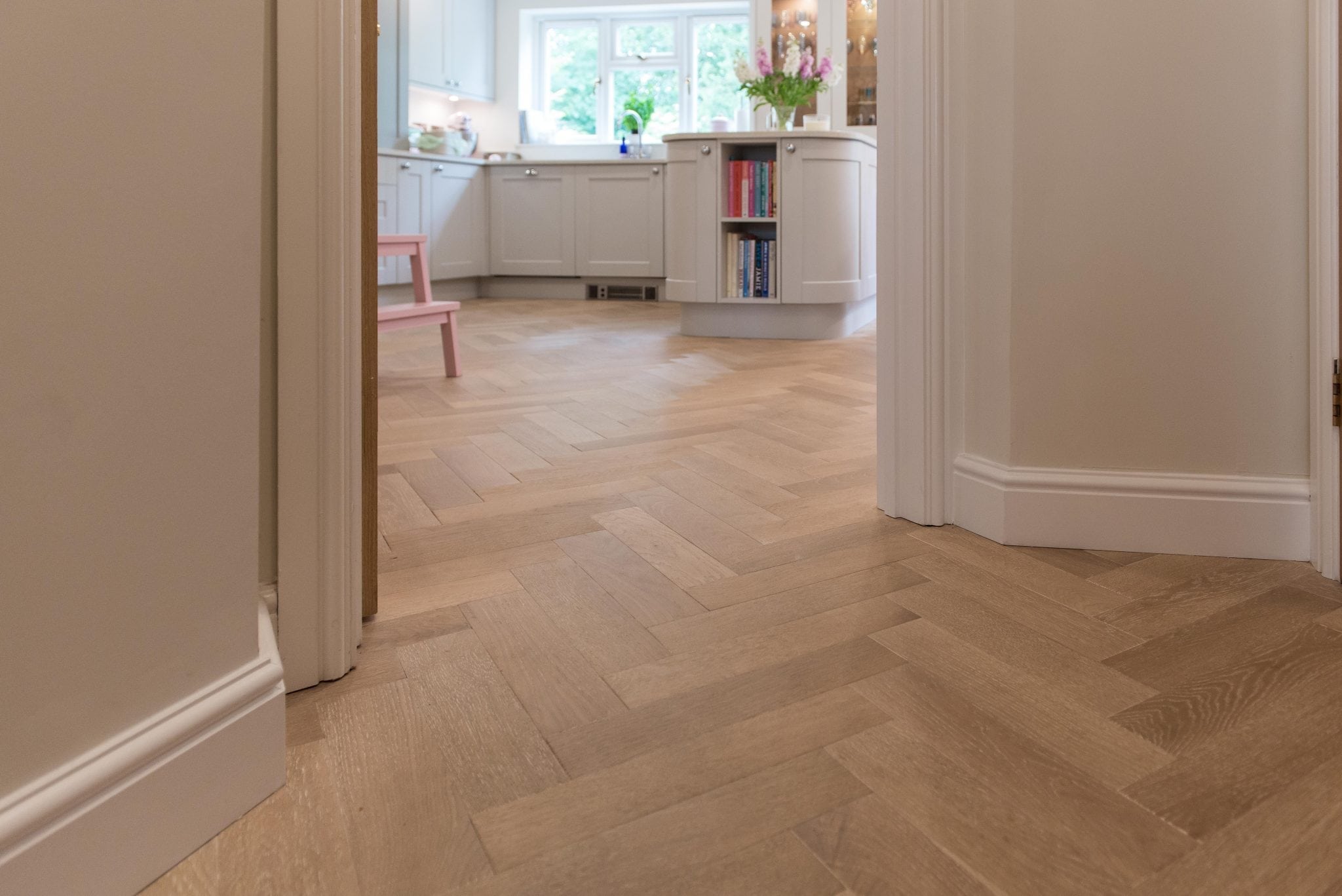 herringbone oak floors in a hallway leading to a kitchen