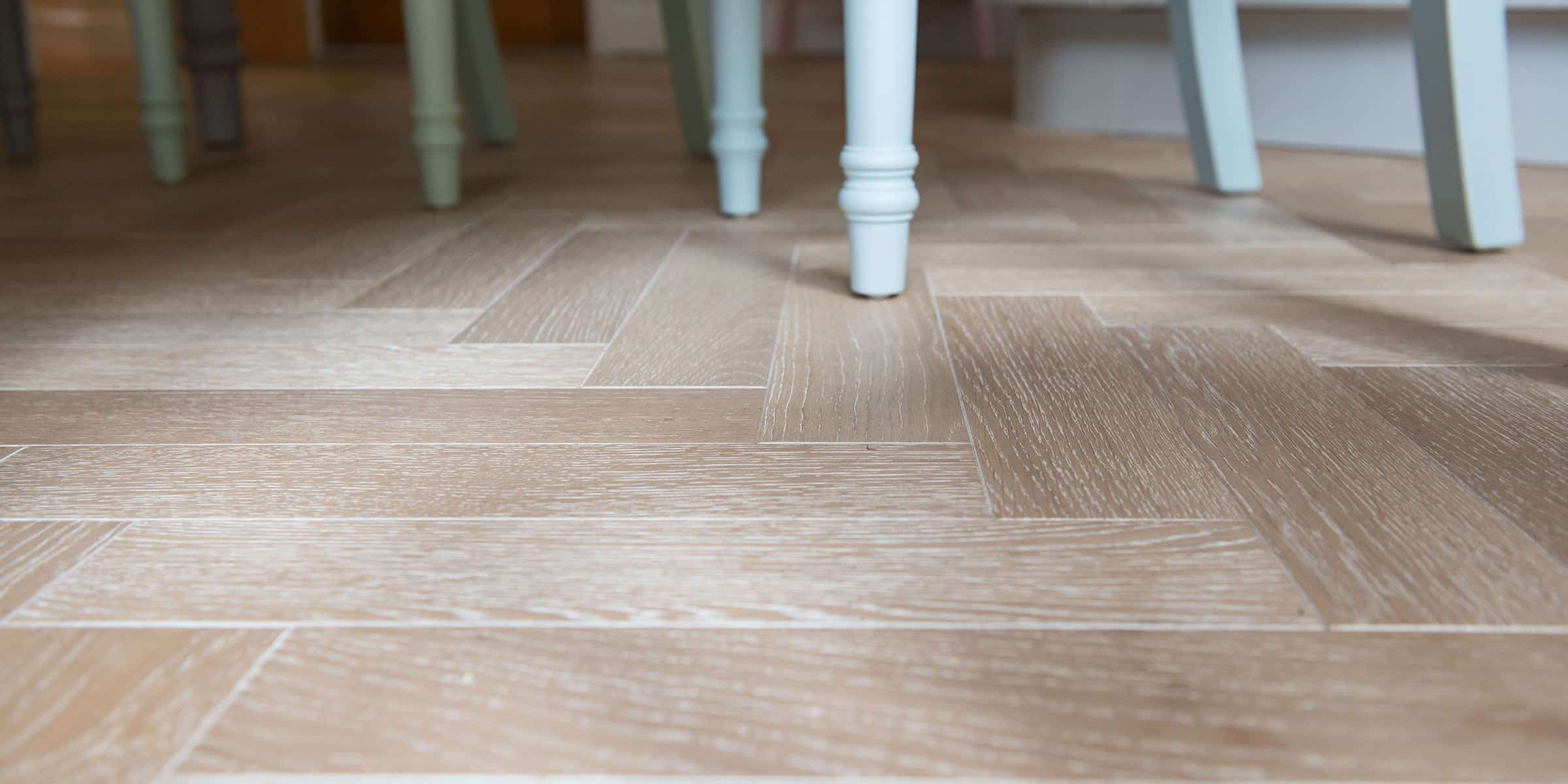 close up of oak herringbone flooring with light blue wooden blue chair legs