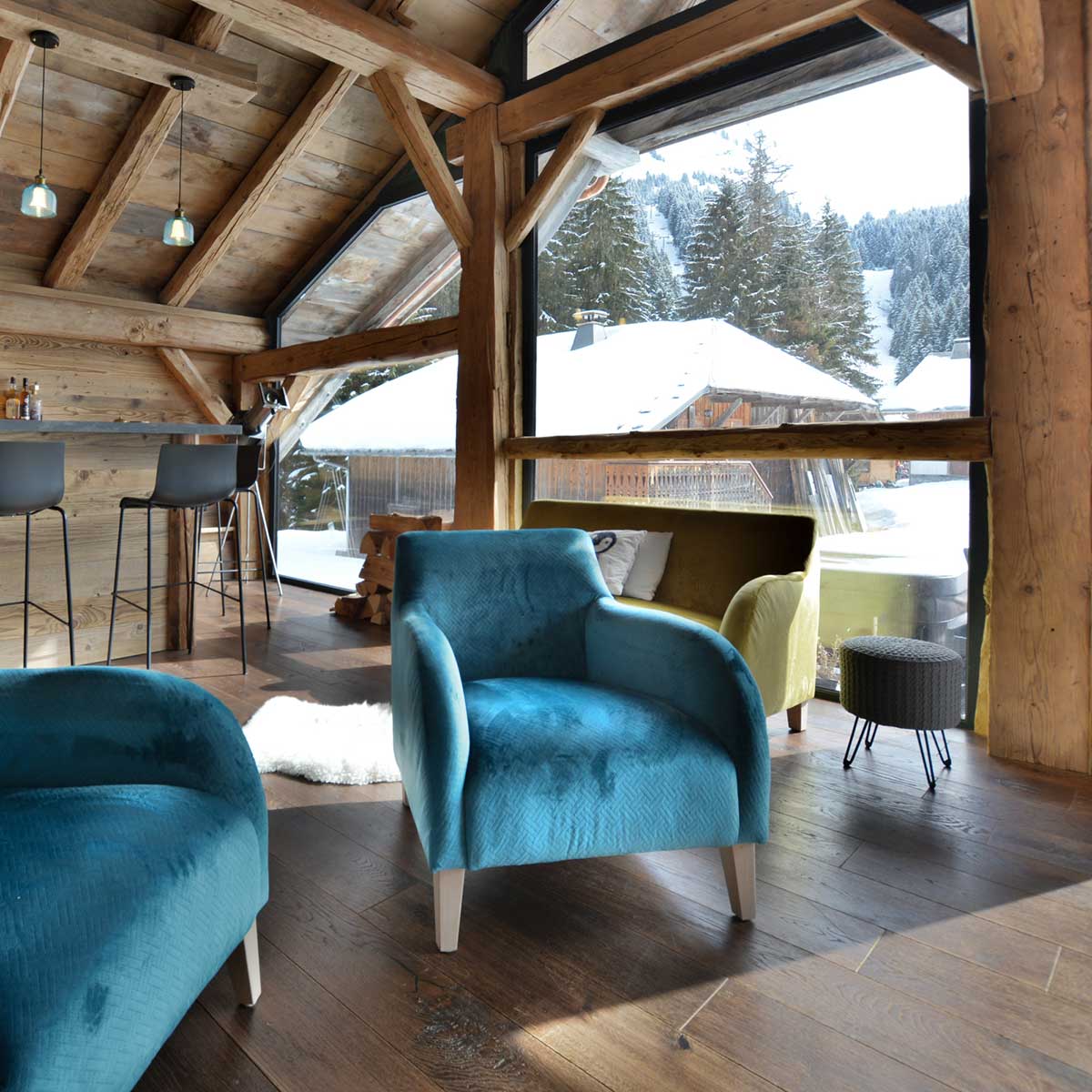 Bright and airy chalet with wood floors and beams, blue arm chairs