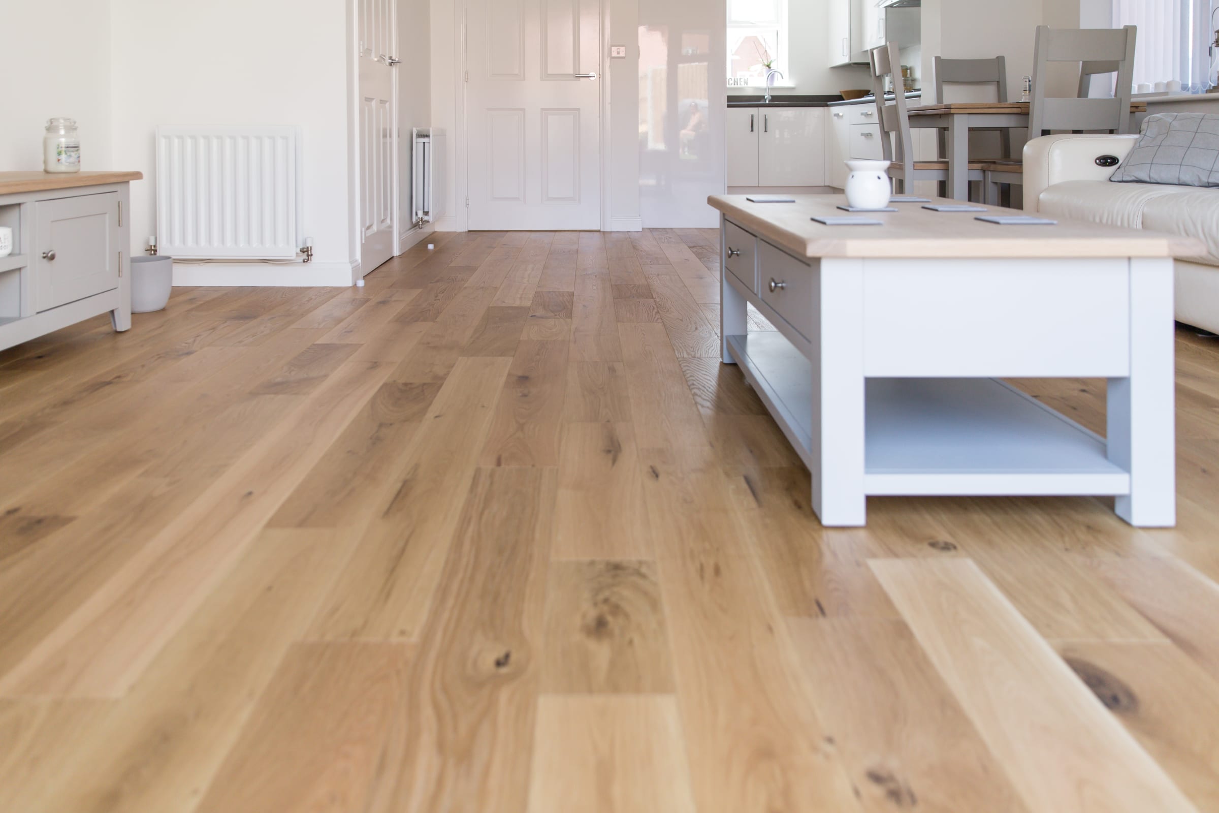 close up of medium toned wood floors in a living room with light coloured furnishings