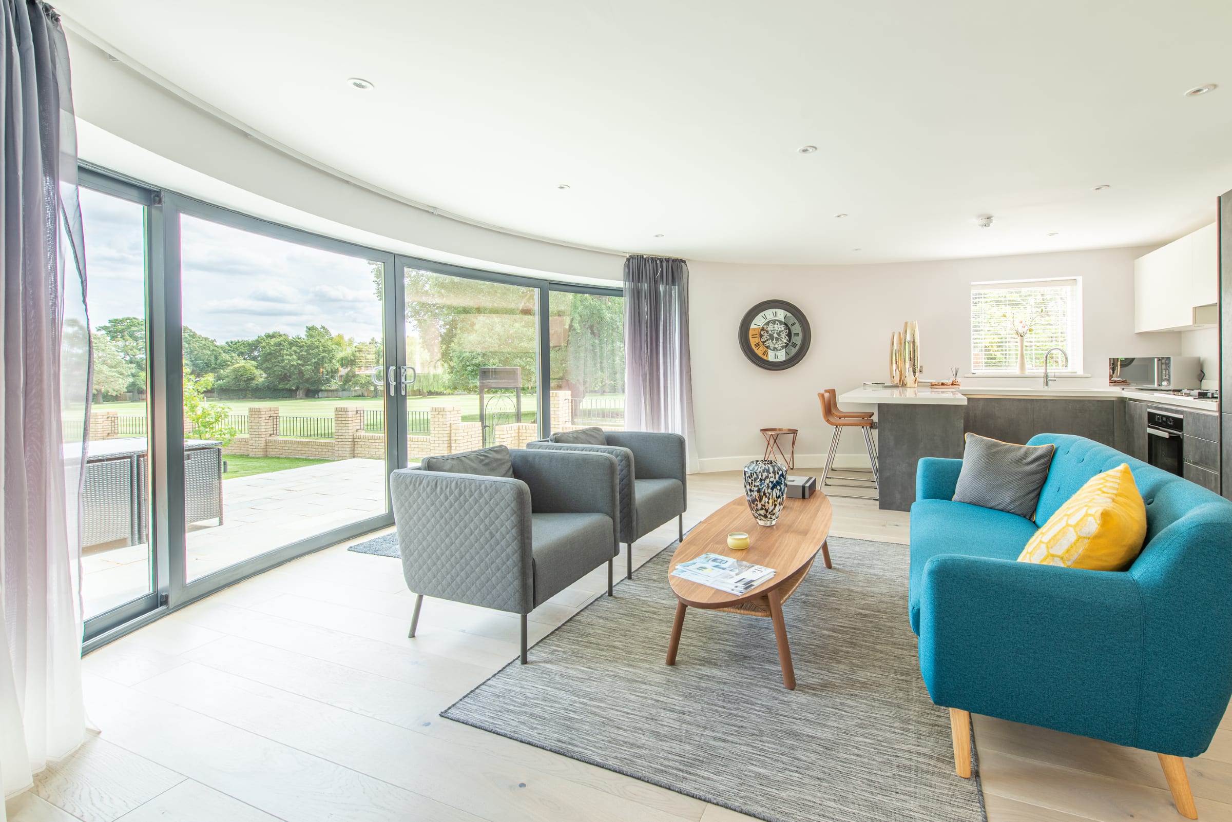 wood flooring in a bright and airy living room, blue and grey sofas, yellow cushions