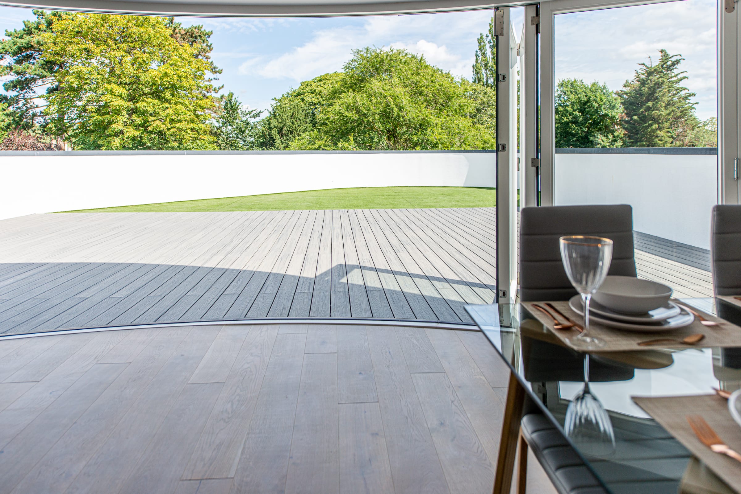 warm toned wood floors leading out onto a wooden patio and back garden