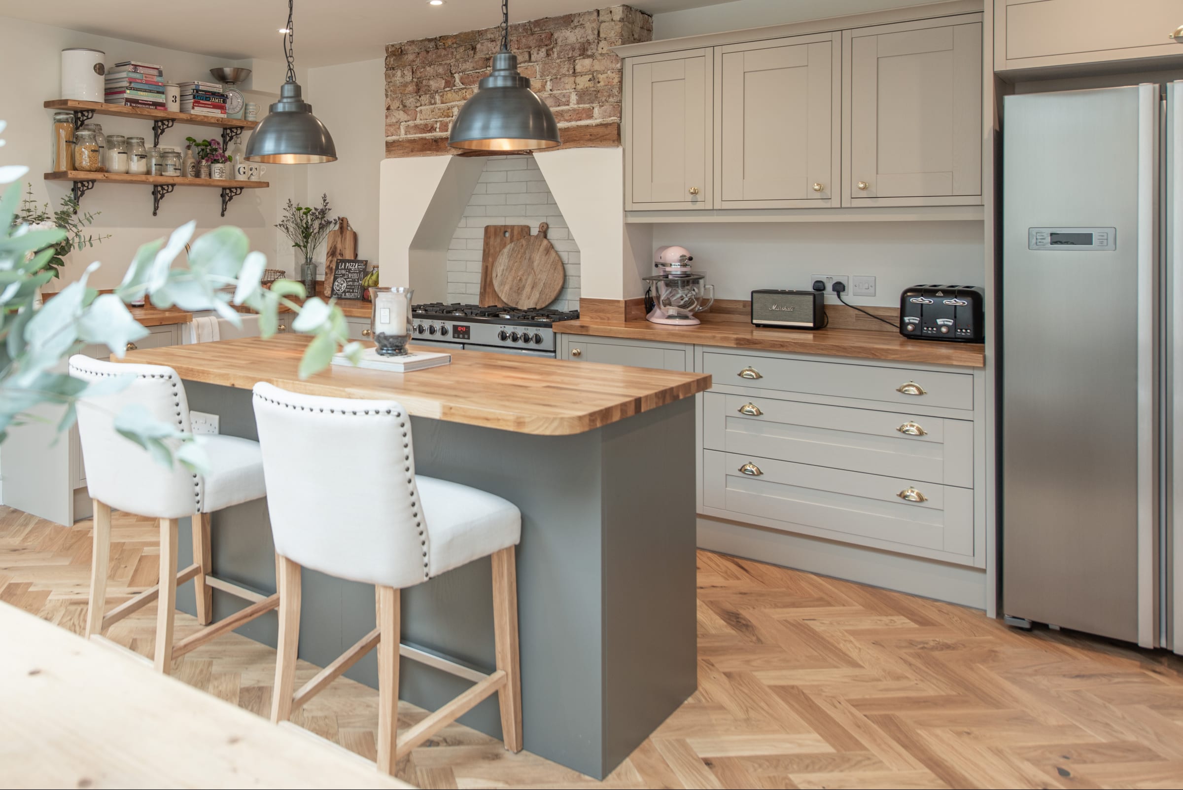 a modern kitchen with green and sage cabinets and herringbone wood floors