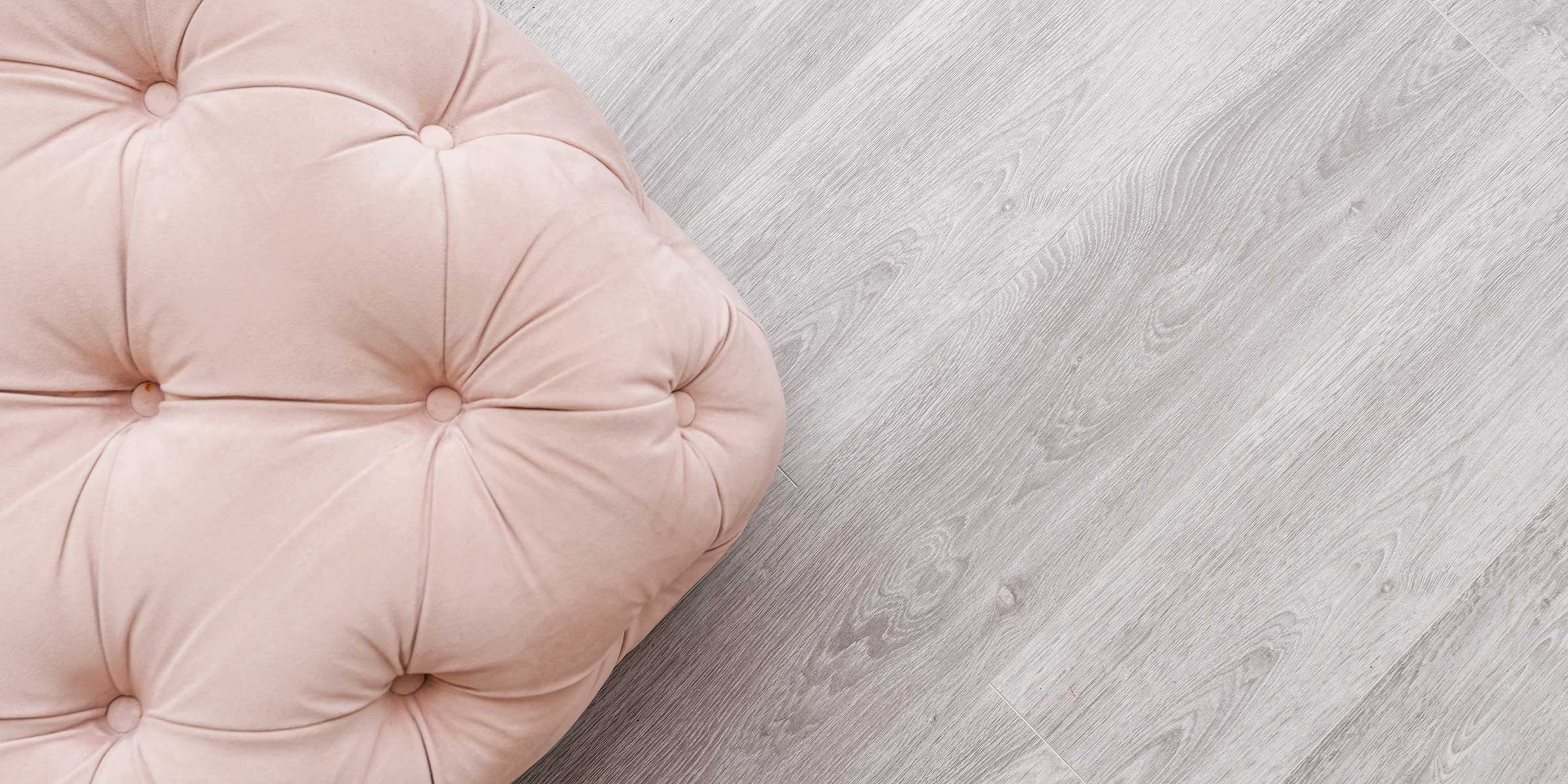 a pink cushion on a light coloured laminate floor