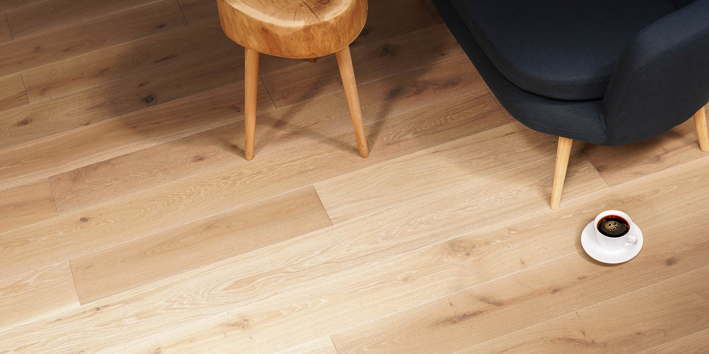 light engineered oak plank with a small wooden stool and dark coloured furnishings