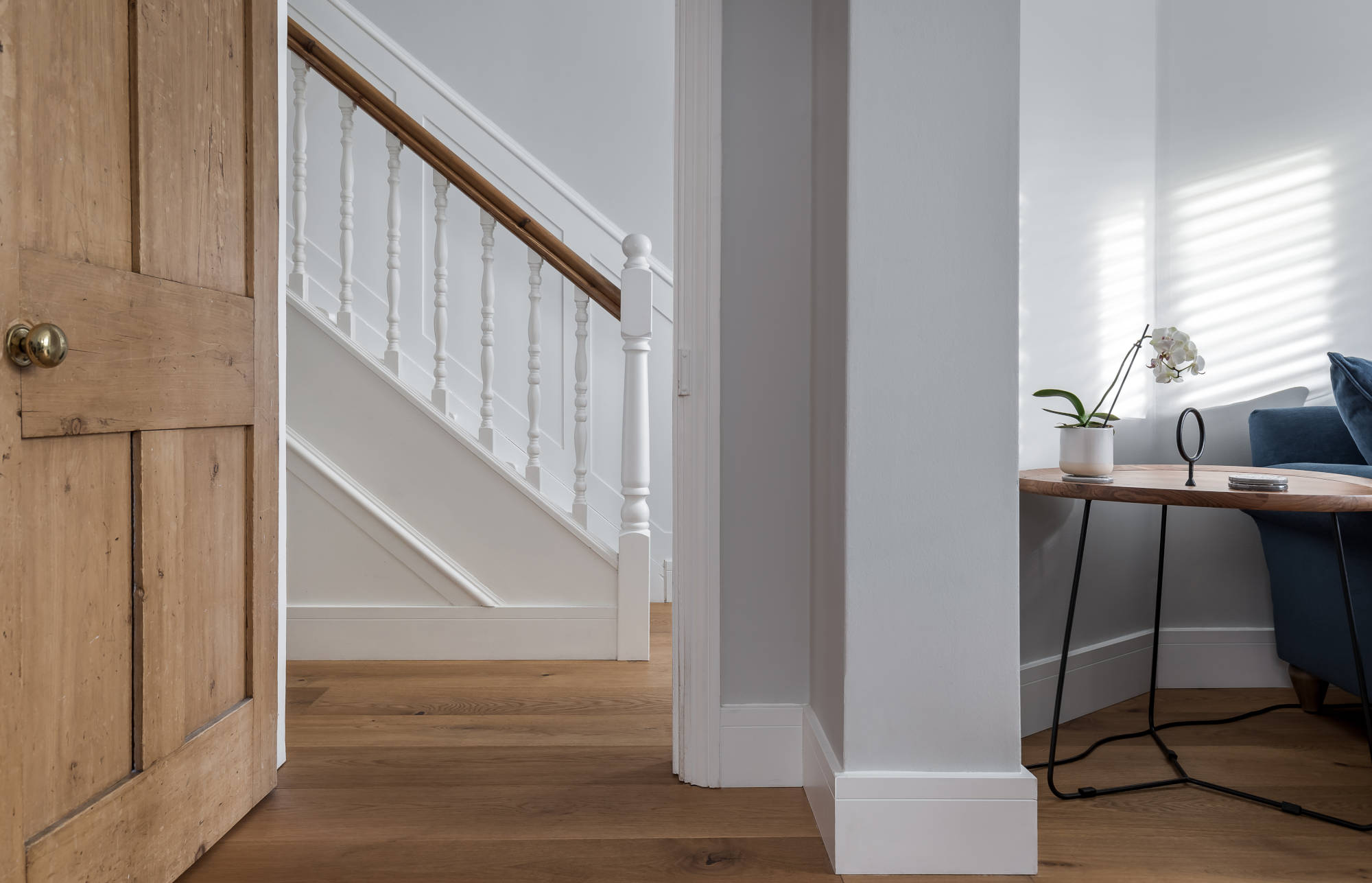 hallway and view of staircase and banister, white walls and oak wood floors