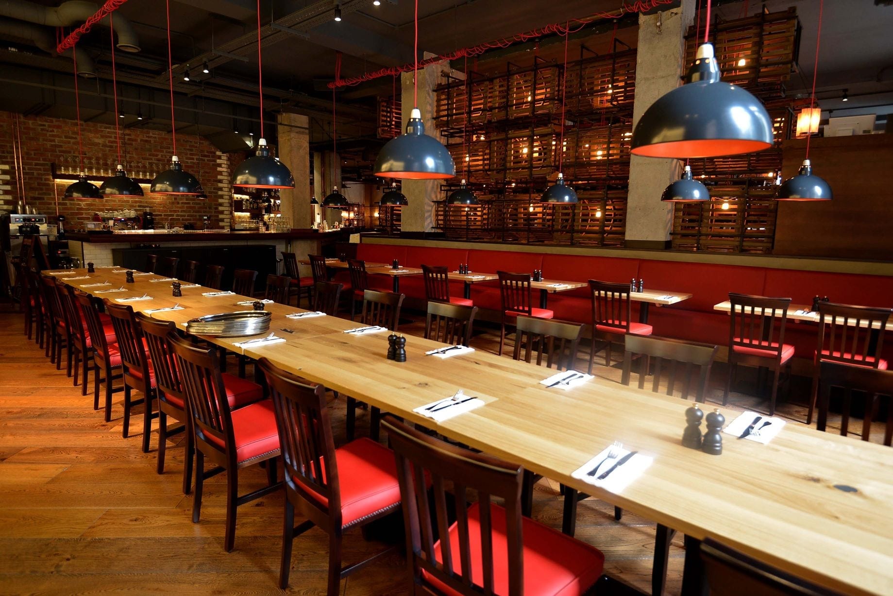 Long table with red chairs and oak wood floors