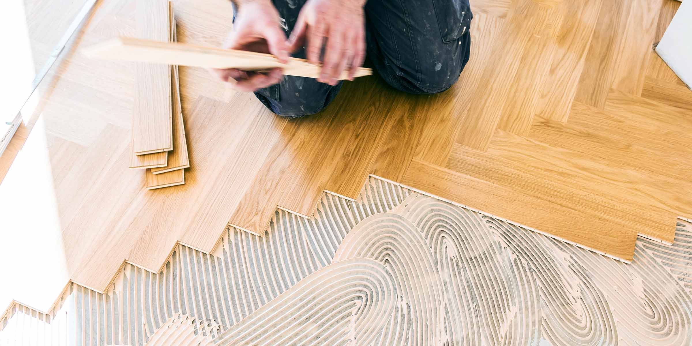 a person installing oak wood floor slats in a herringbone pattern