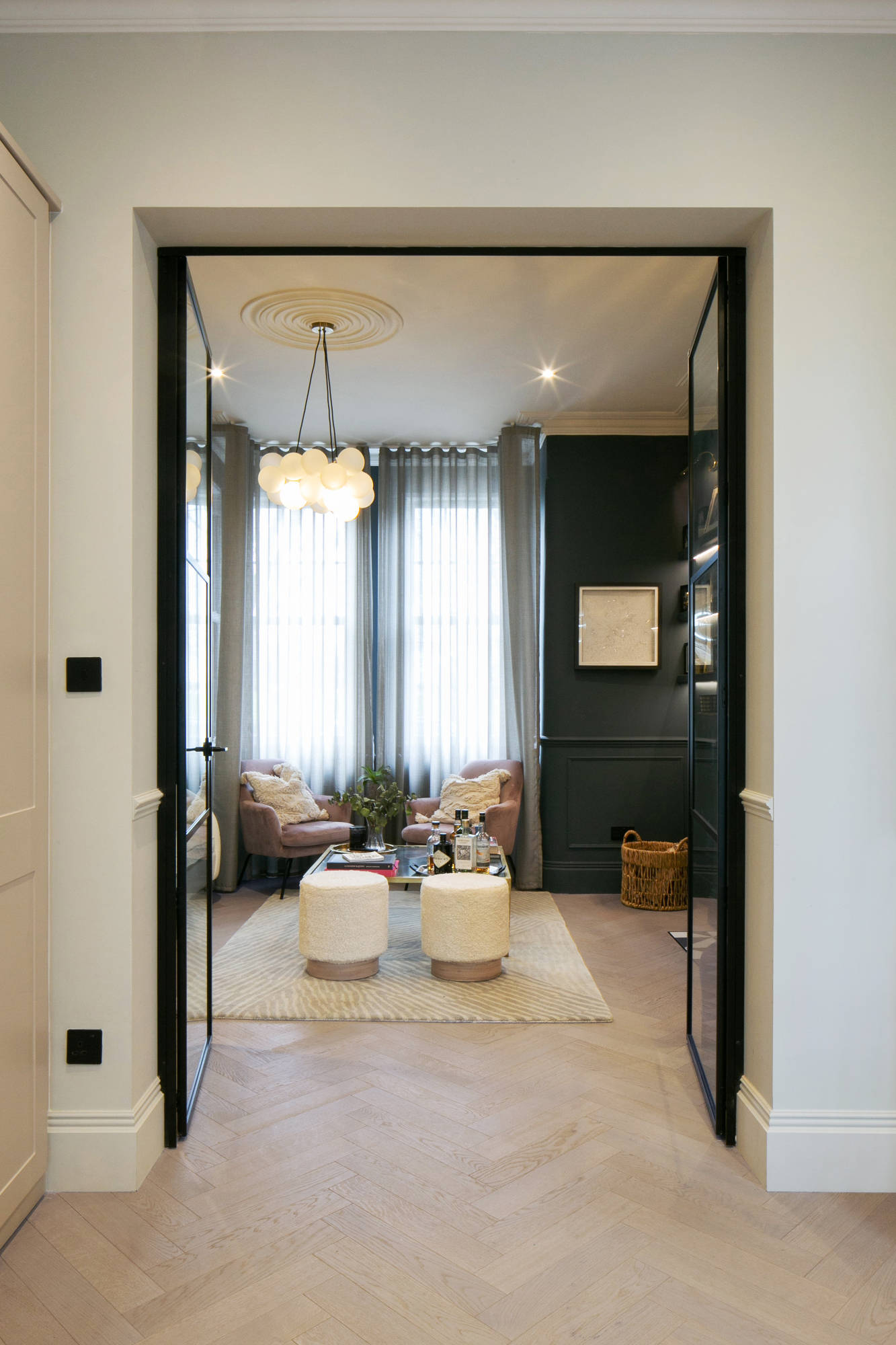 oak wood floor in a hallway looking into the living room, large windows and luxury furnishings