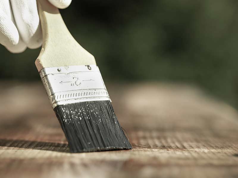 a person brushing oil onto oak wood floors, wood floor care