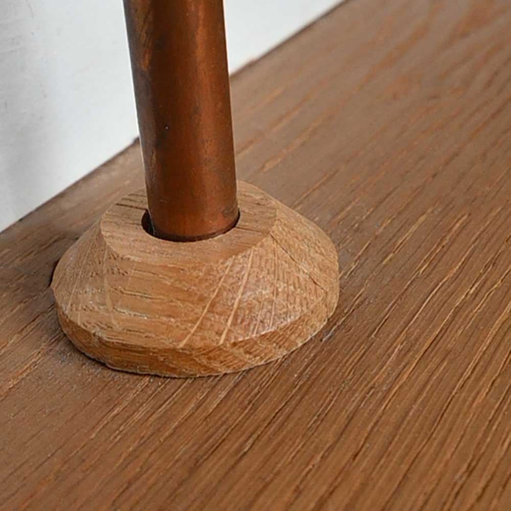 wooden oak pipe cover hiding the bottom of a copper pipe