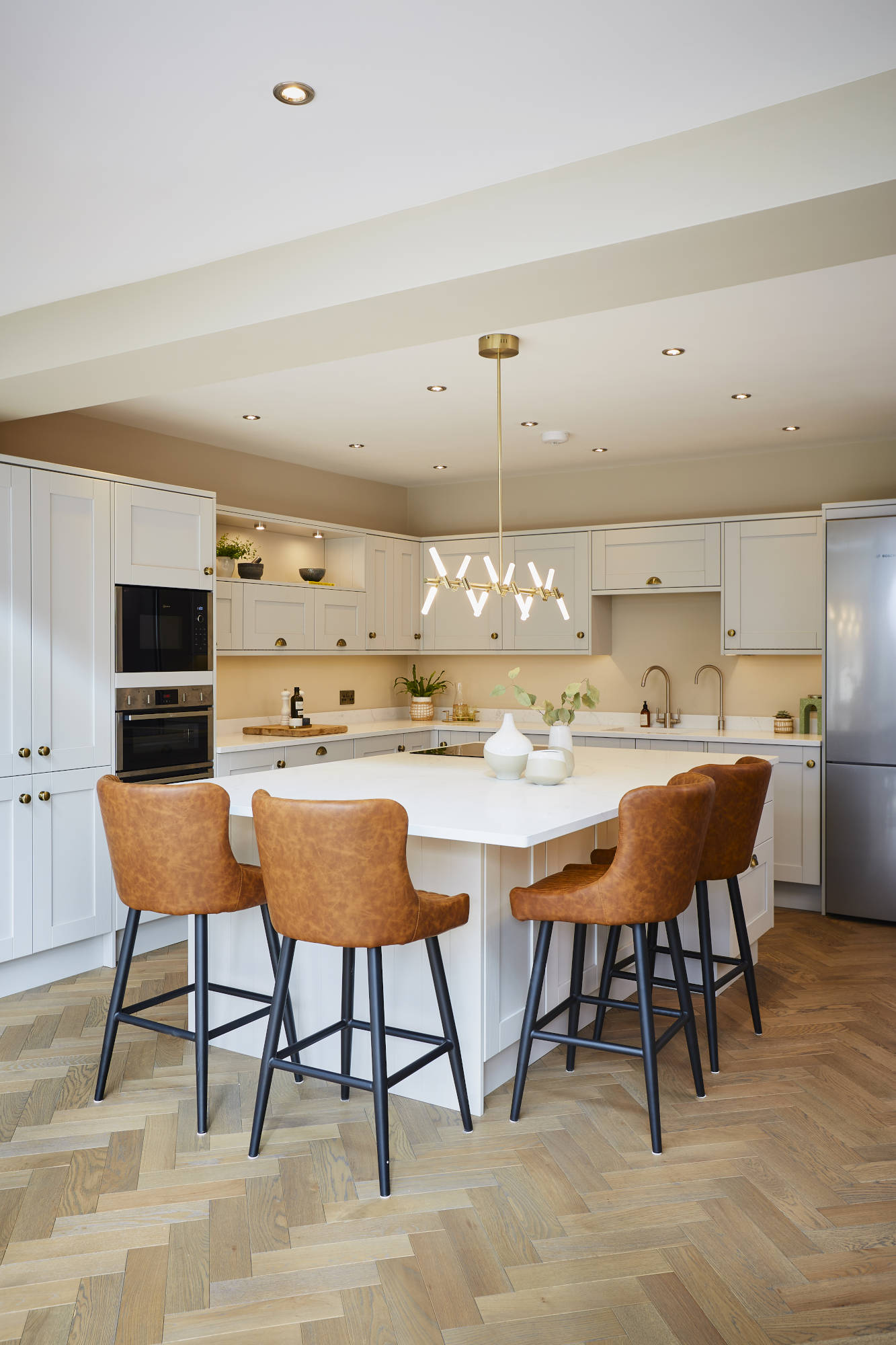 stylish white kitchen cupboards and island featuring a herringbone oak wood floor