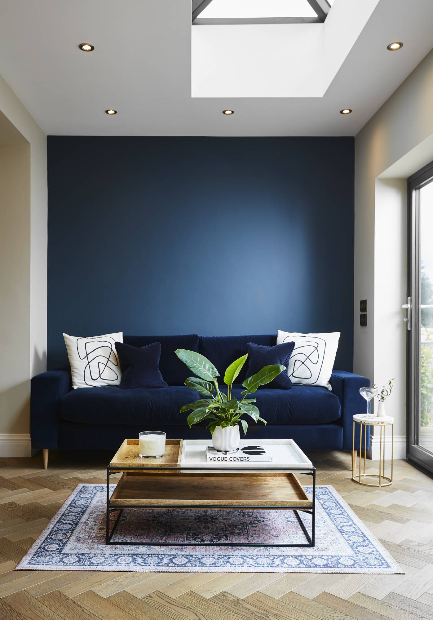 Dark velvet blue couch and midnight blue wall on a natural sustainable oak flooring