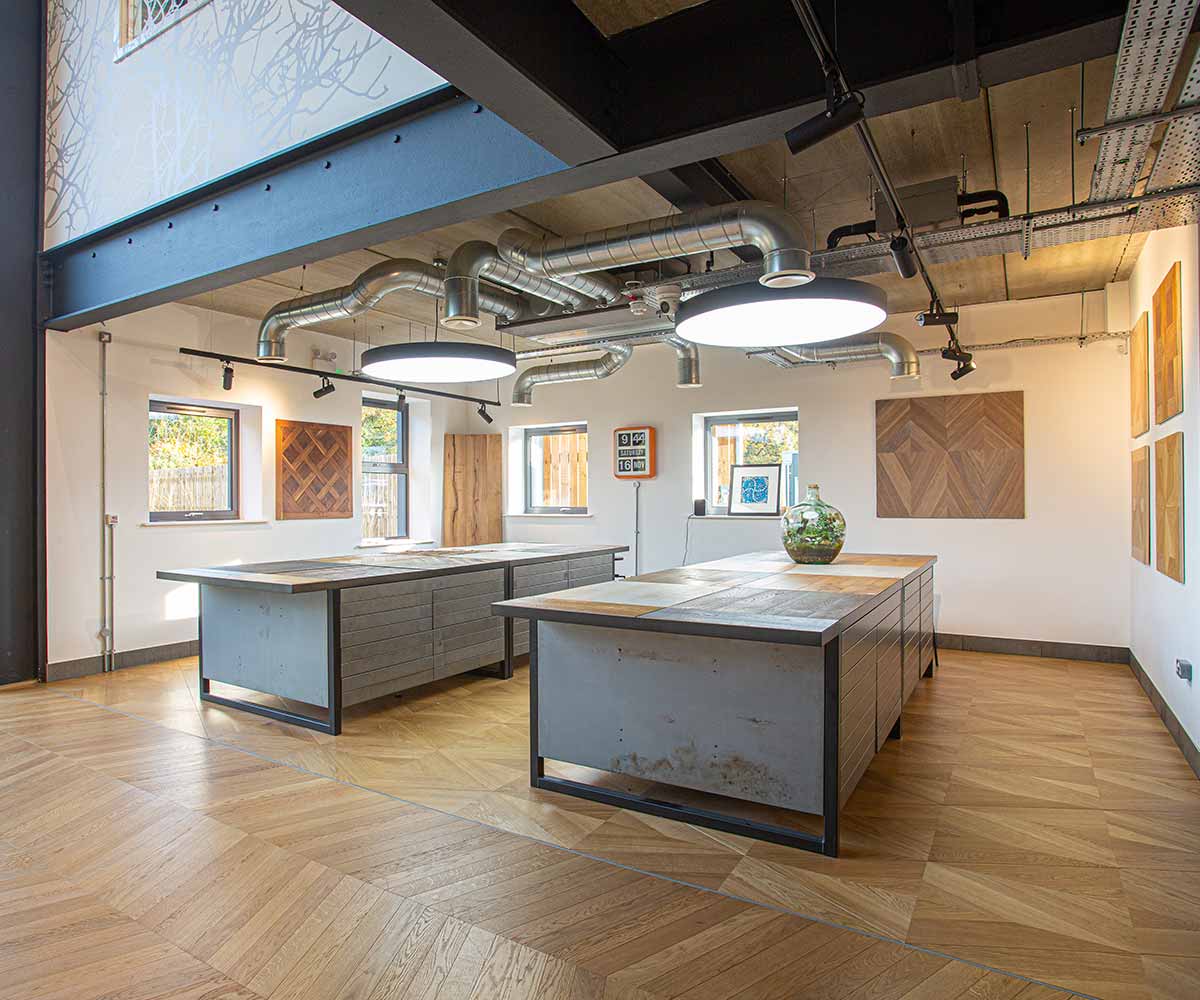 interior photo of the Surrey Design Centre. Two desks sit in the middle of the room with oak wood flooring samples