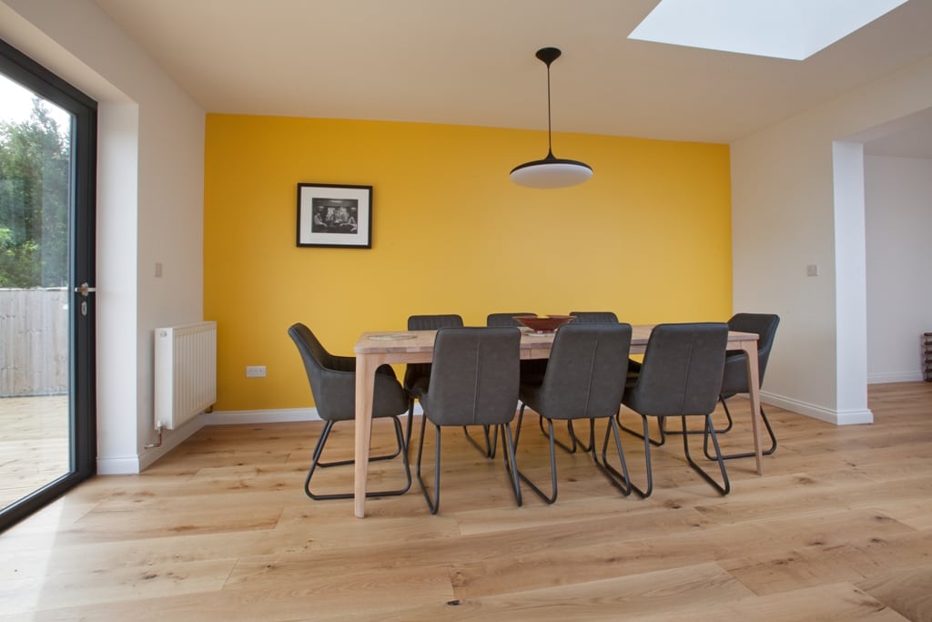 wide plank oak wood floors with a yellow wall and dining table