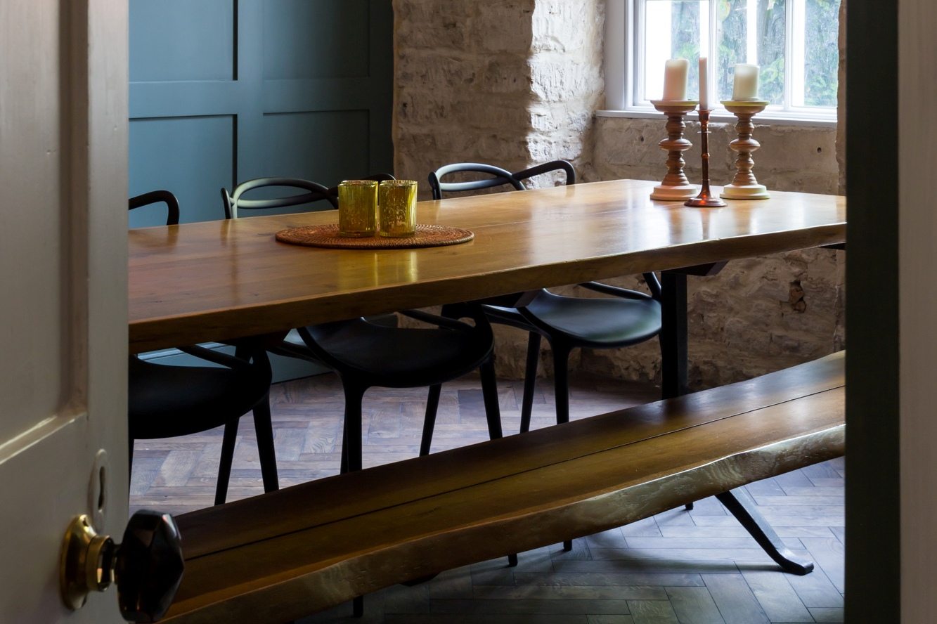 herringbone dark wood floors in a dining room with a wooden table and stylish dark green walls