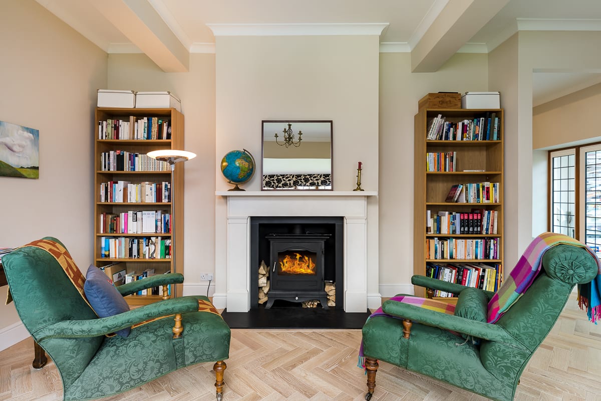 herringbone wood floors in a living room with two bookcases and green armchairs