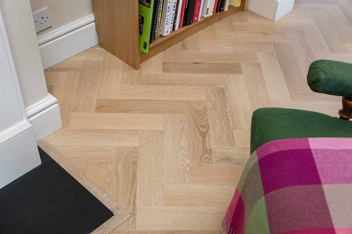 close up of herringbone wood floor with a pink and green blanket