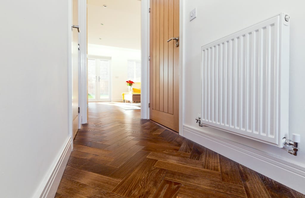 herringbone wood floor in a hallway with white walls and wooden doors