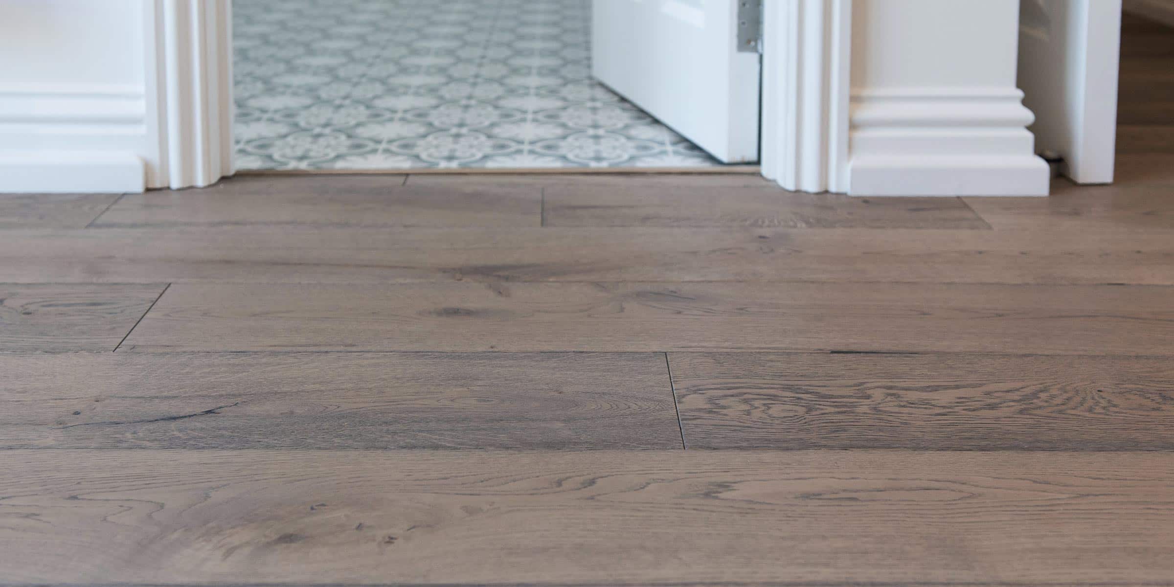 frozen umber wood floors in a hallway, with bathroom tiles in the background