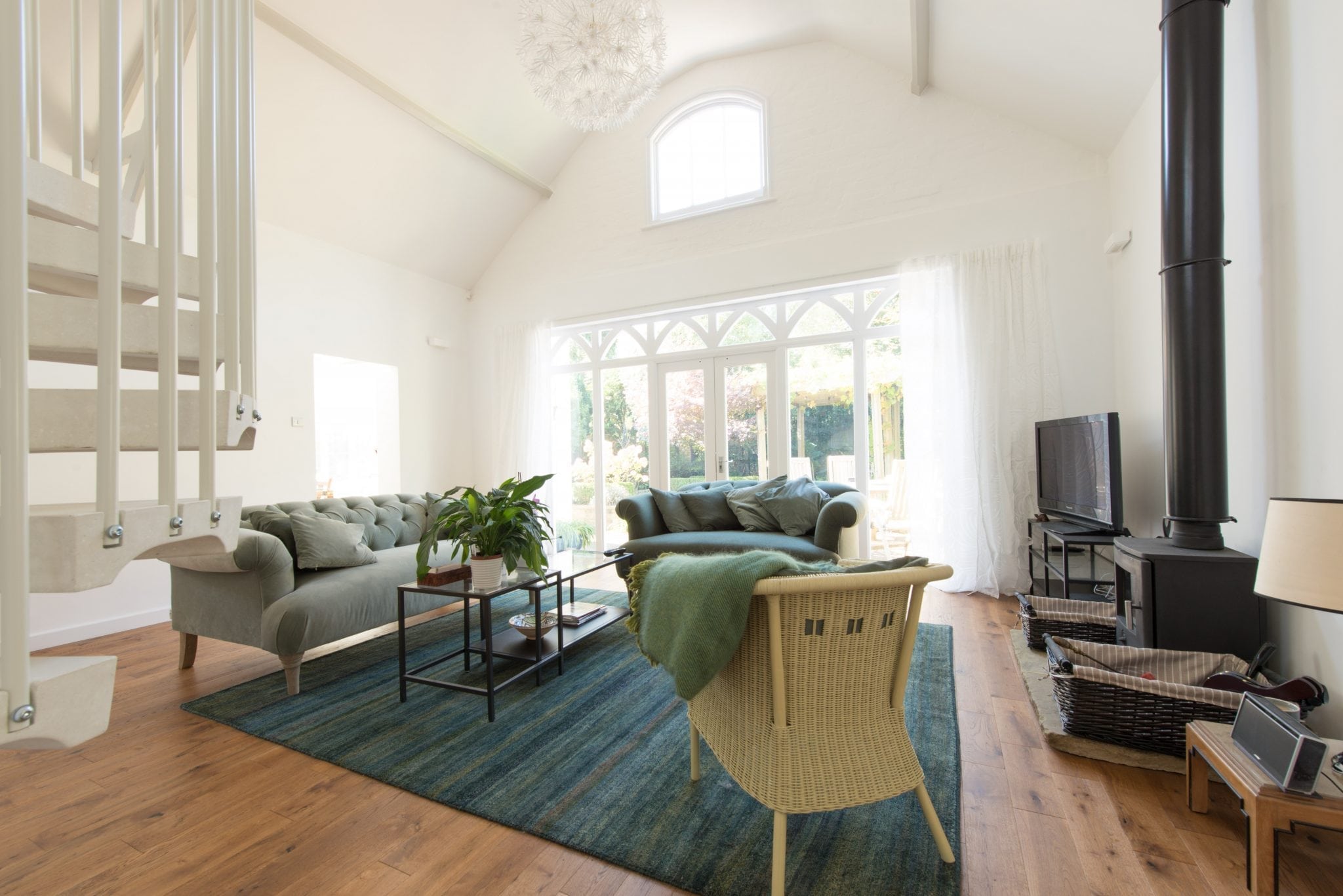 wood floors covered by a blue carpet in a bright living room with large cathedral windows