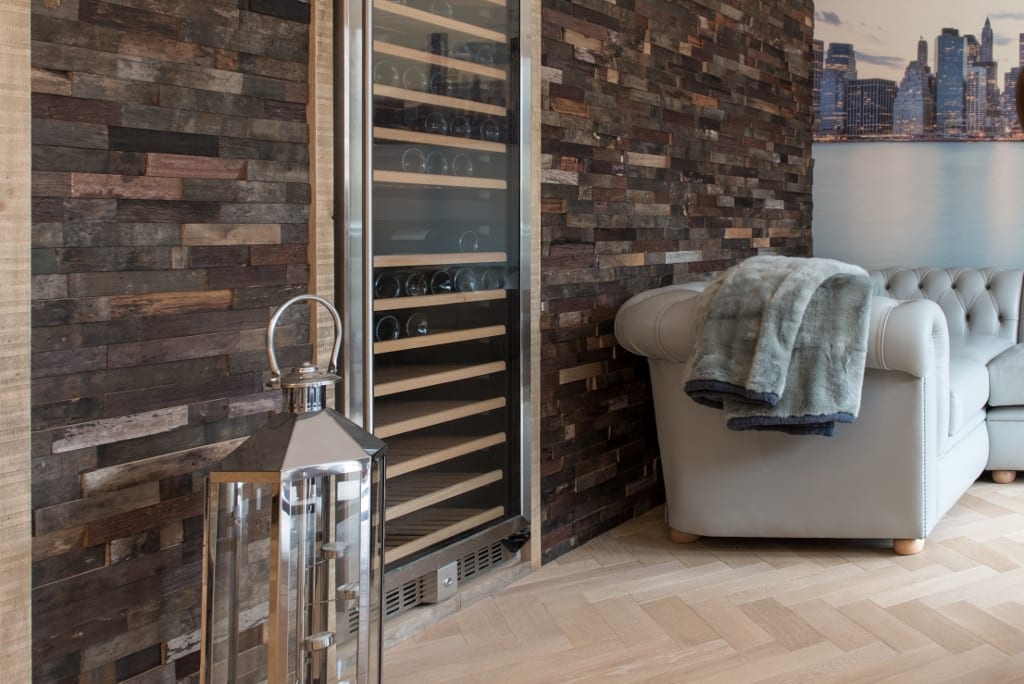 herringbone wood floors with a wooden panelled wall and wine fridge