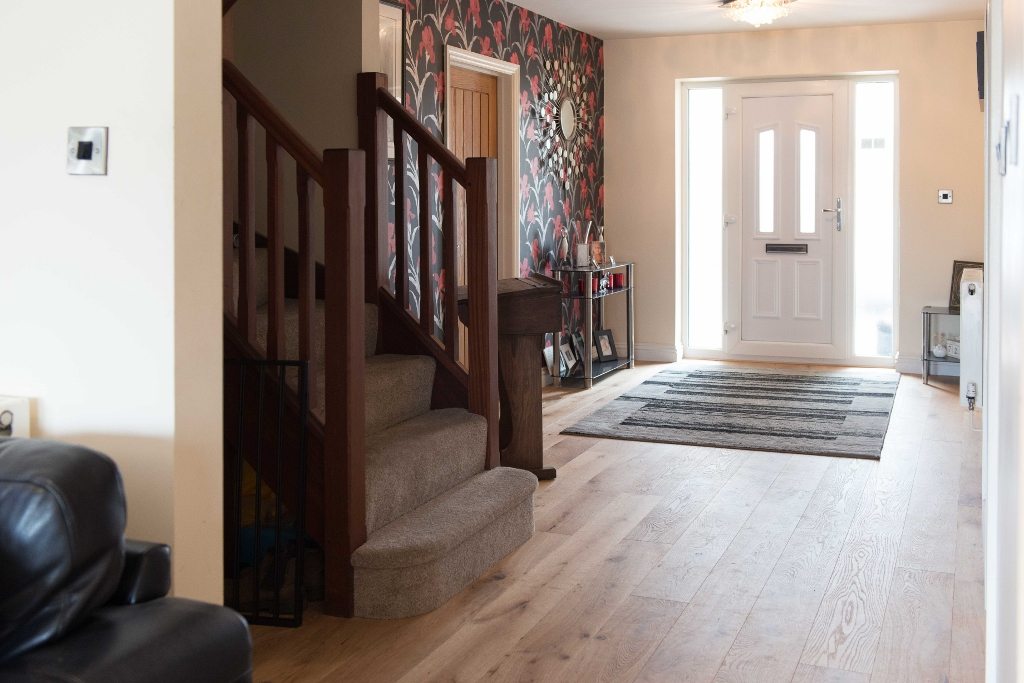 a hallway with a stair case and front door and oak wood flooring