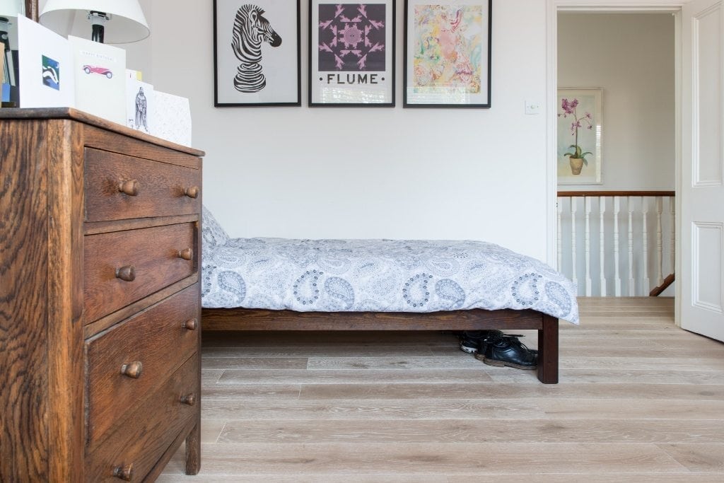 Nordic beach light wood flooring in a bedroom, with a close up of dark wood chest of drawers