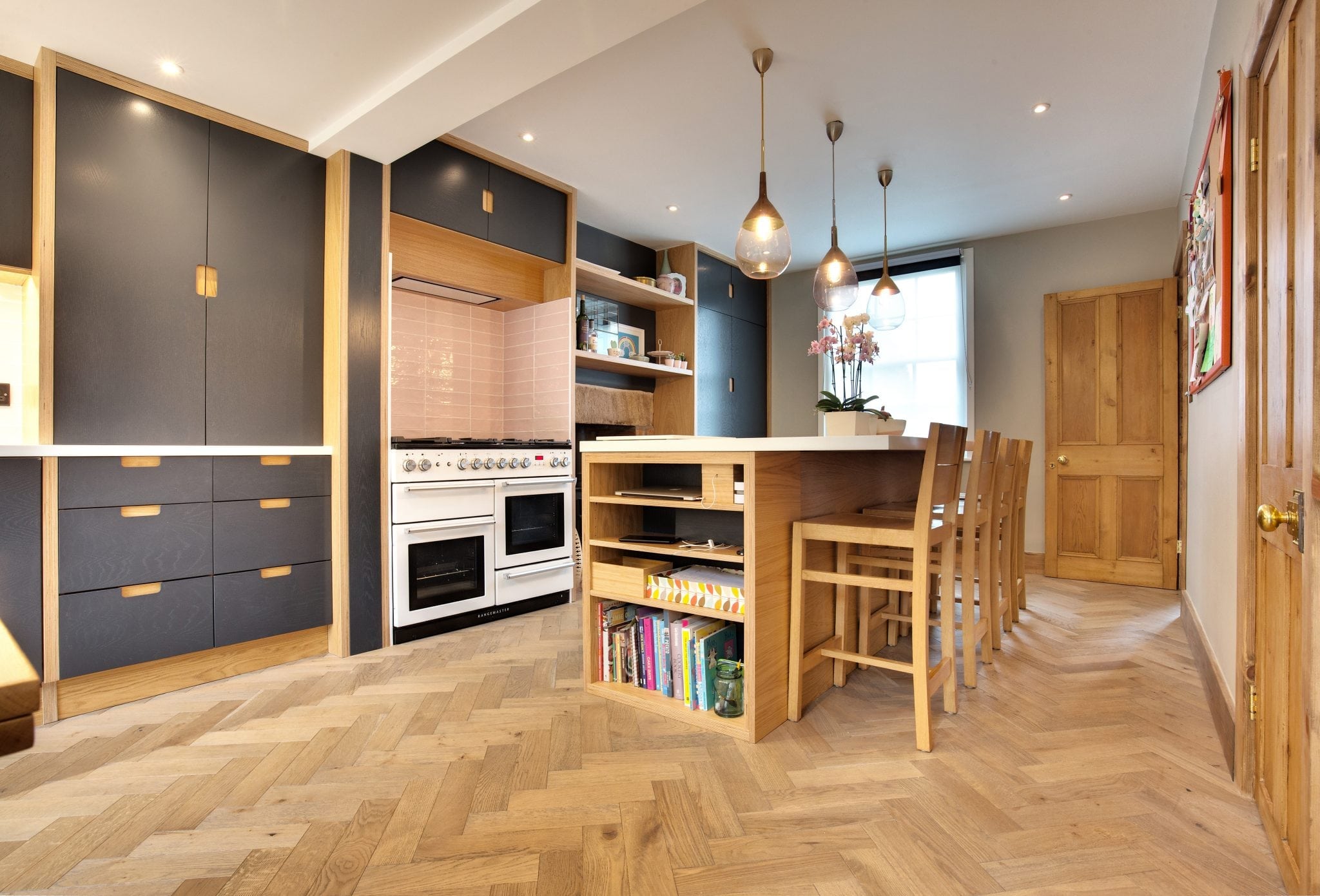 herringbone wood floors in a modern kitchen with wooden features and navy blue cabinets