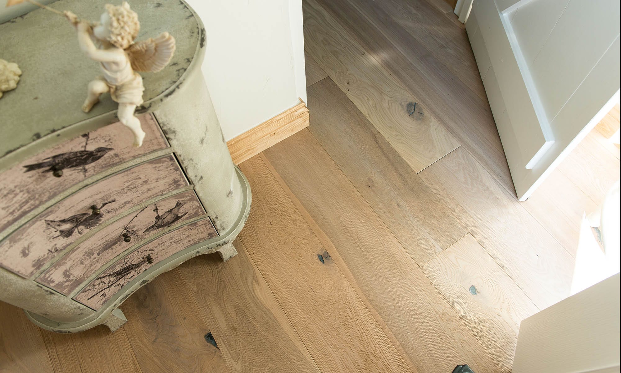 close up of oak wood floors with a distressed light green chest of drawers