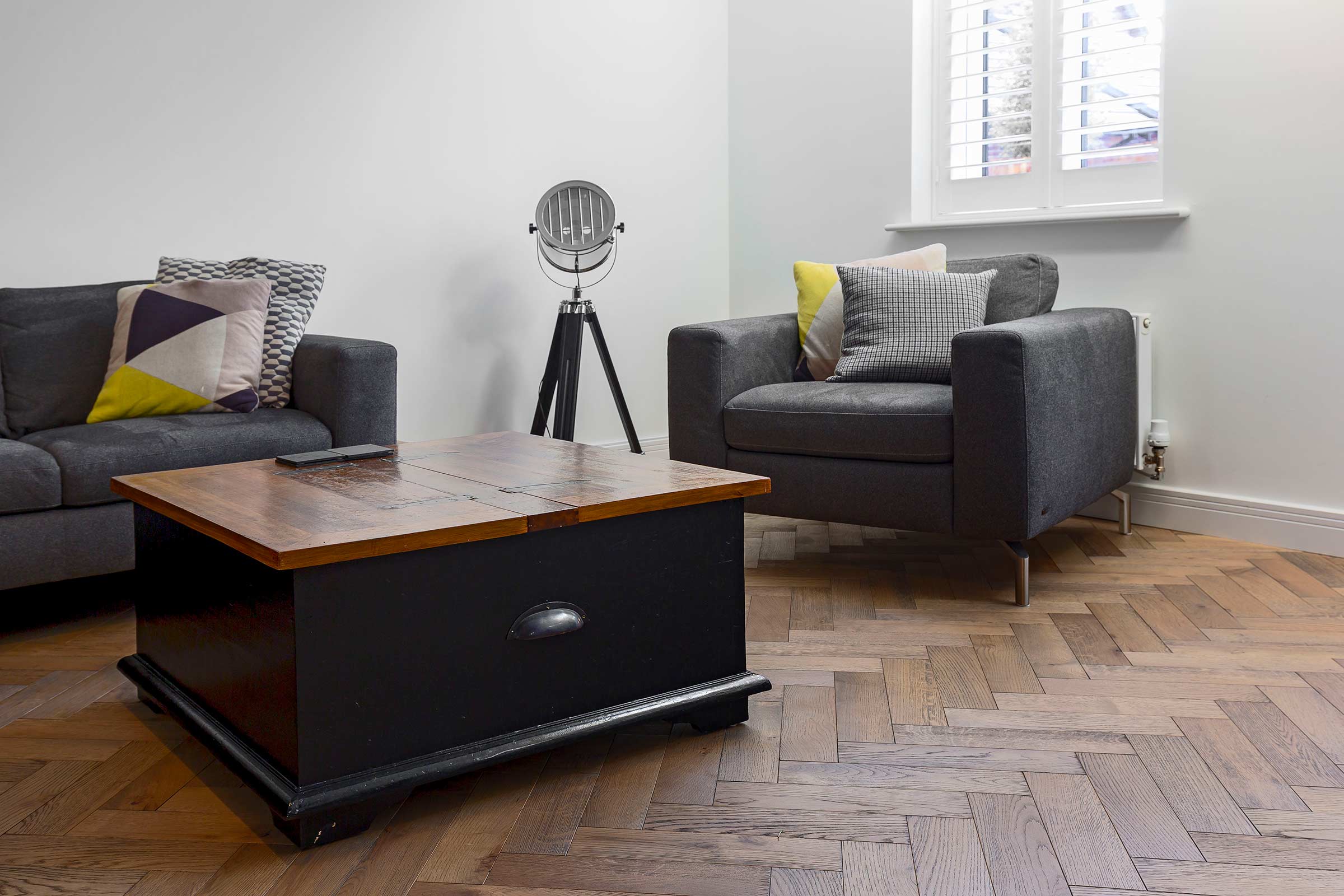 herringbone floor with a grey sofa and blue and wood table